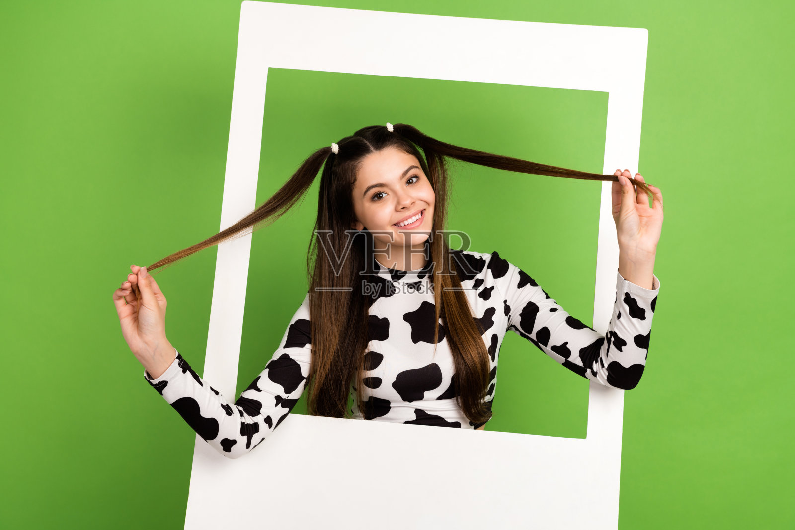 兴奋搞笑的女孩穿着牛皮上衣,手持尾巴在绿色背景下拍照照片摄影图片