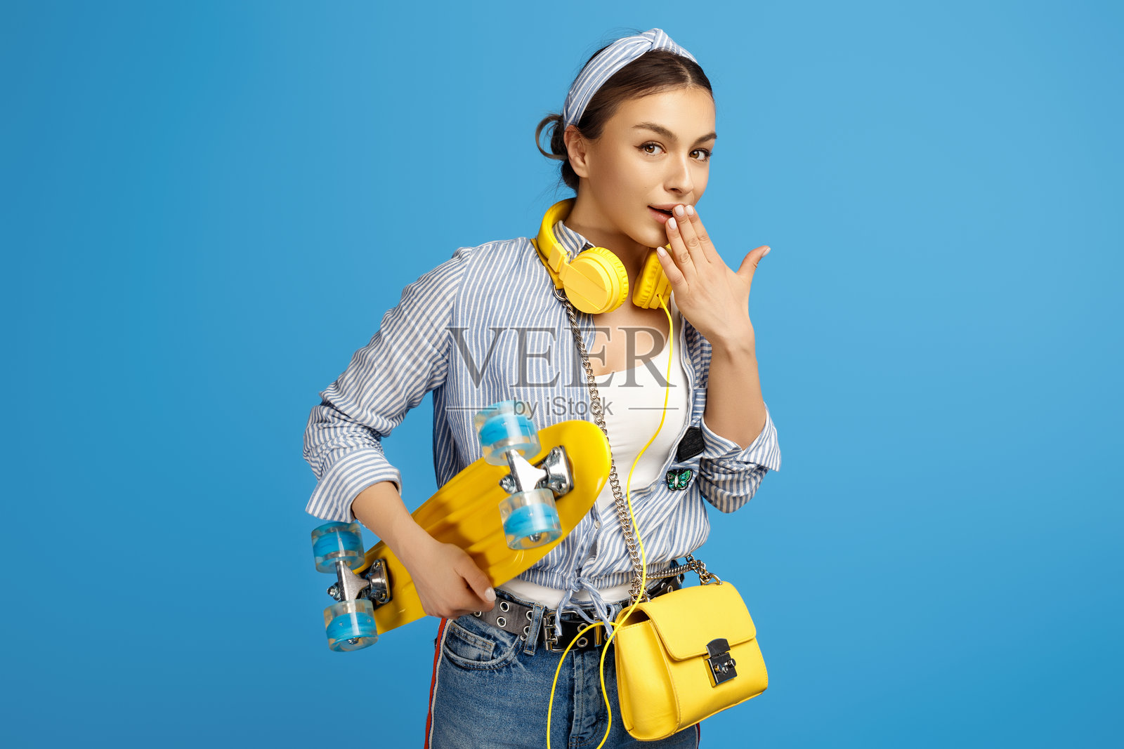 兴奋的年轻女性与黄色滑板或滑板车、足球和耳机的照片照片摄影图片