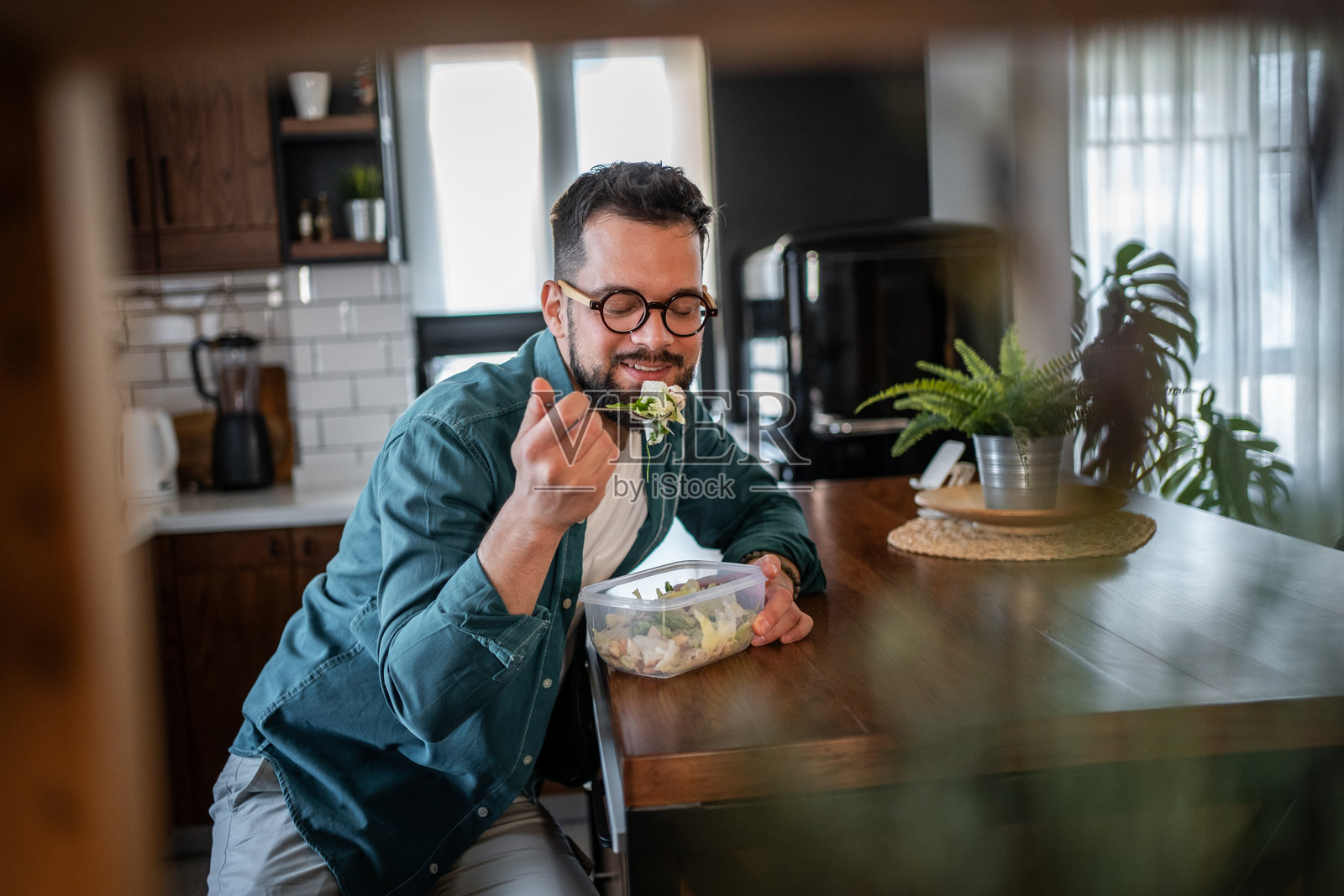 年轻男子在现代厨房里享用健康沙拉照片摄影图片