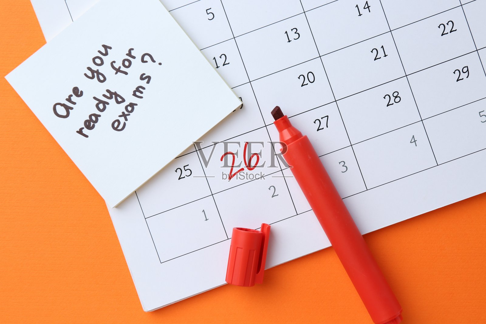 橙色背景上的纸条,上面写着“你准备好考试了吗?”以及文具,俯视图。照片摄影图片