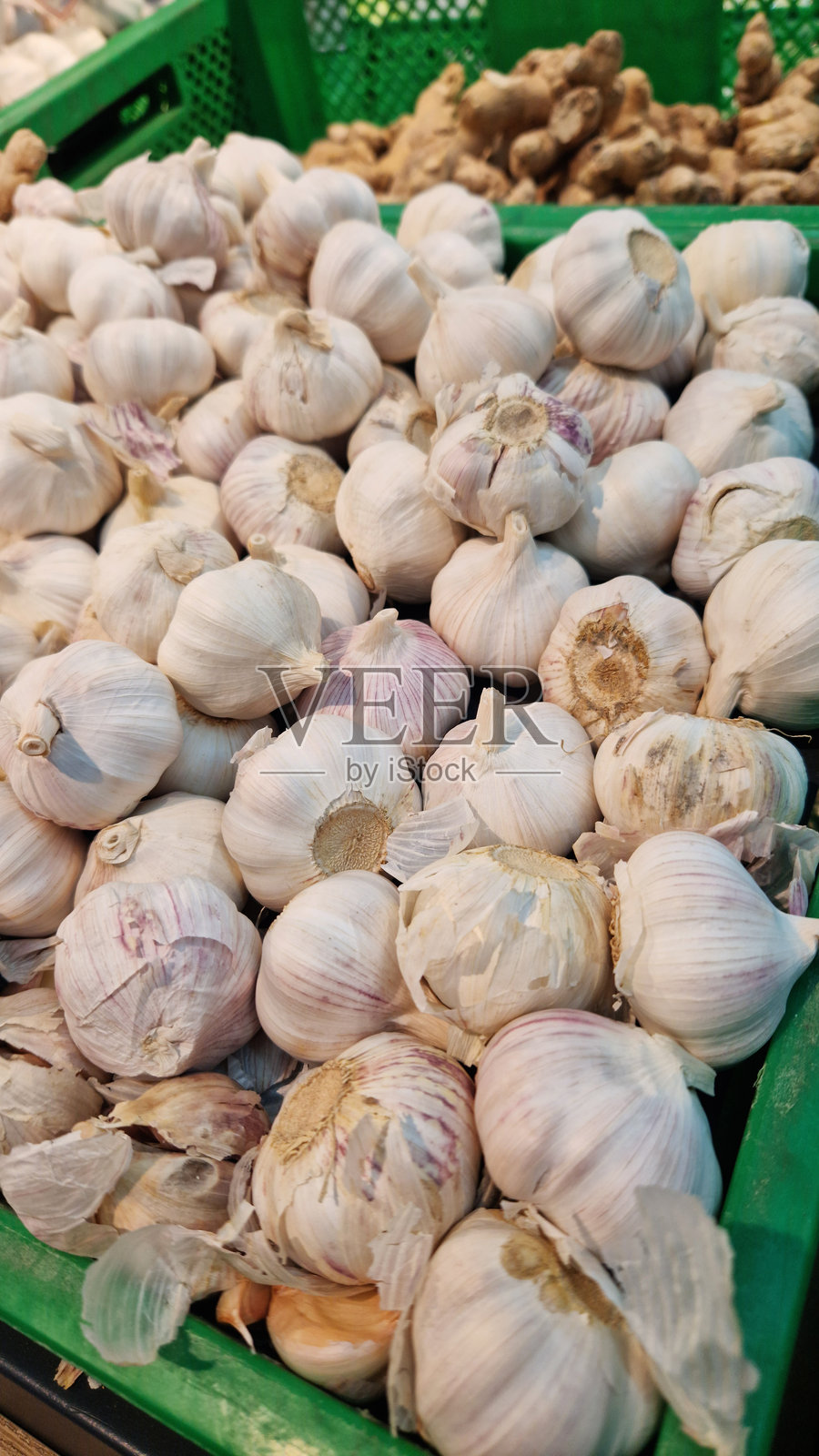 市场摊位上的绿色塑料箱里装满了大蒜照片摄影图片