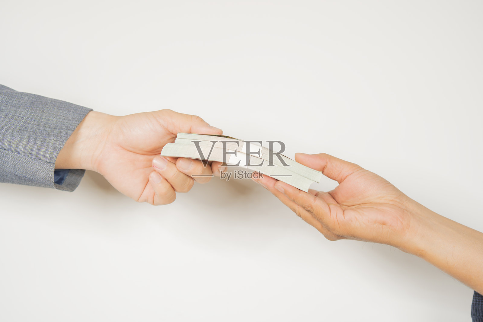 两个人的手握着两叠美元钞票,背景为白色。照片摄影图片
