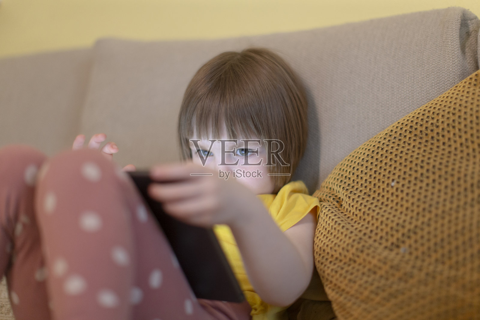 一个孩子在舒适的沙发上专注于平板电脑,周围环境温馨宜人照片摄影图片