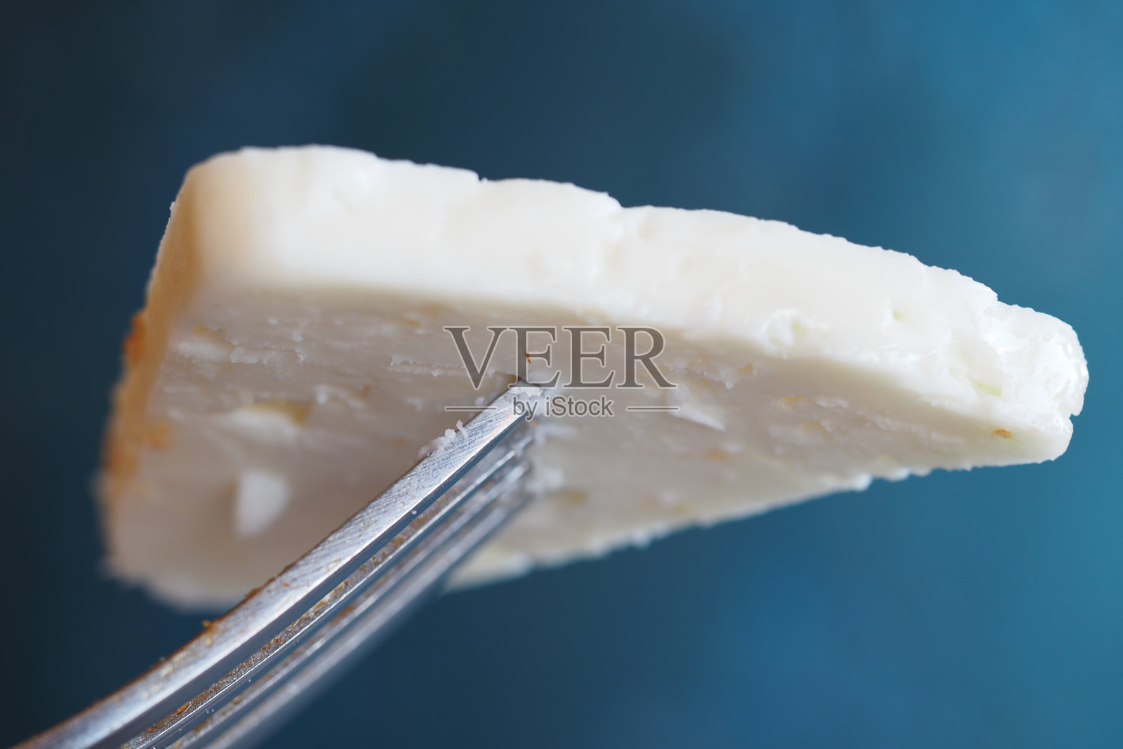 美味的白色奶酪叉在叉子上,准备享用照片摄影图片