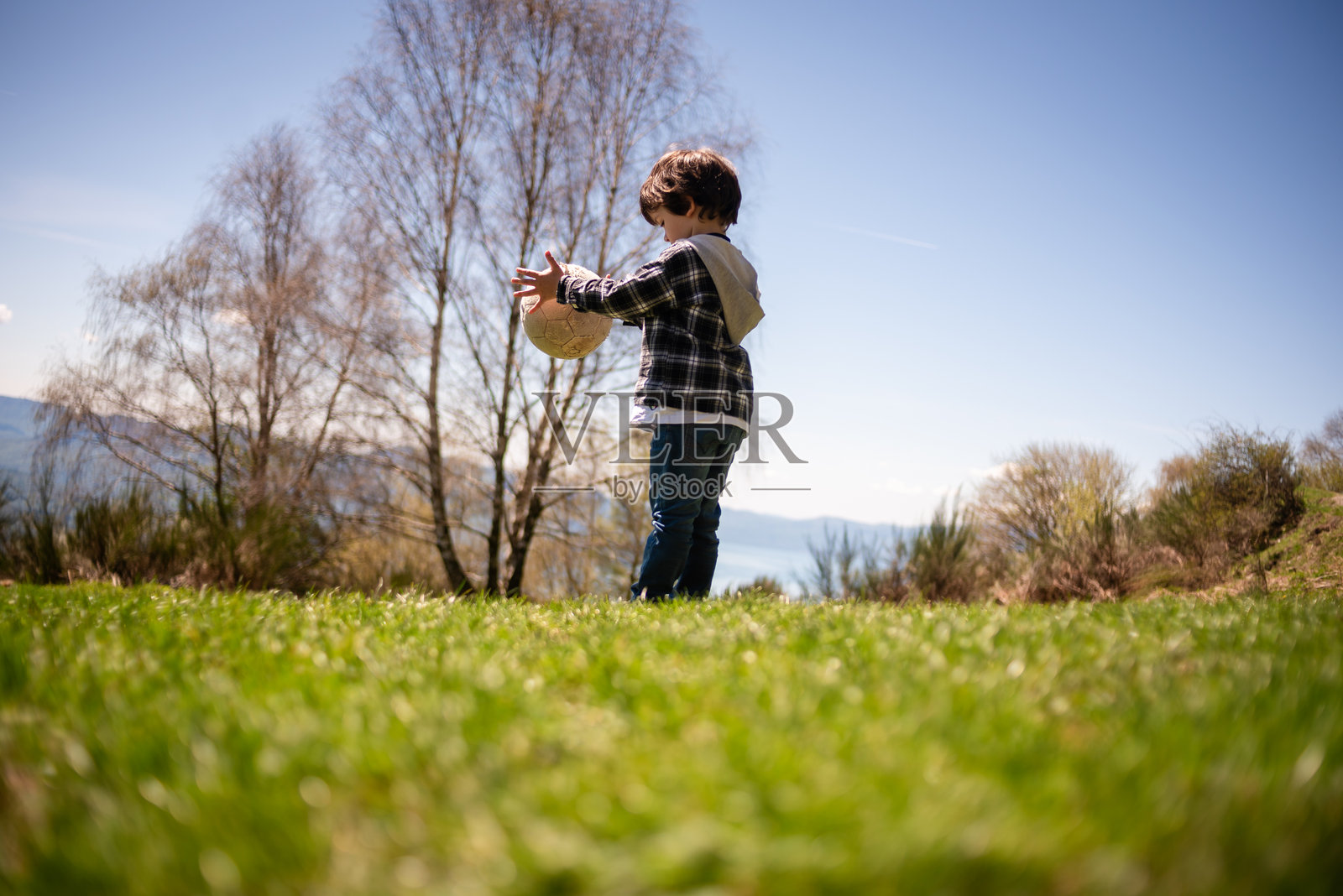 孩子在阳光明媚的田野里玩球照片摄影图片