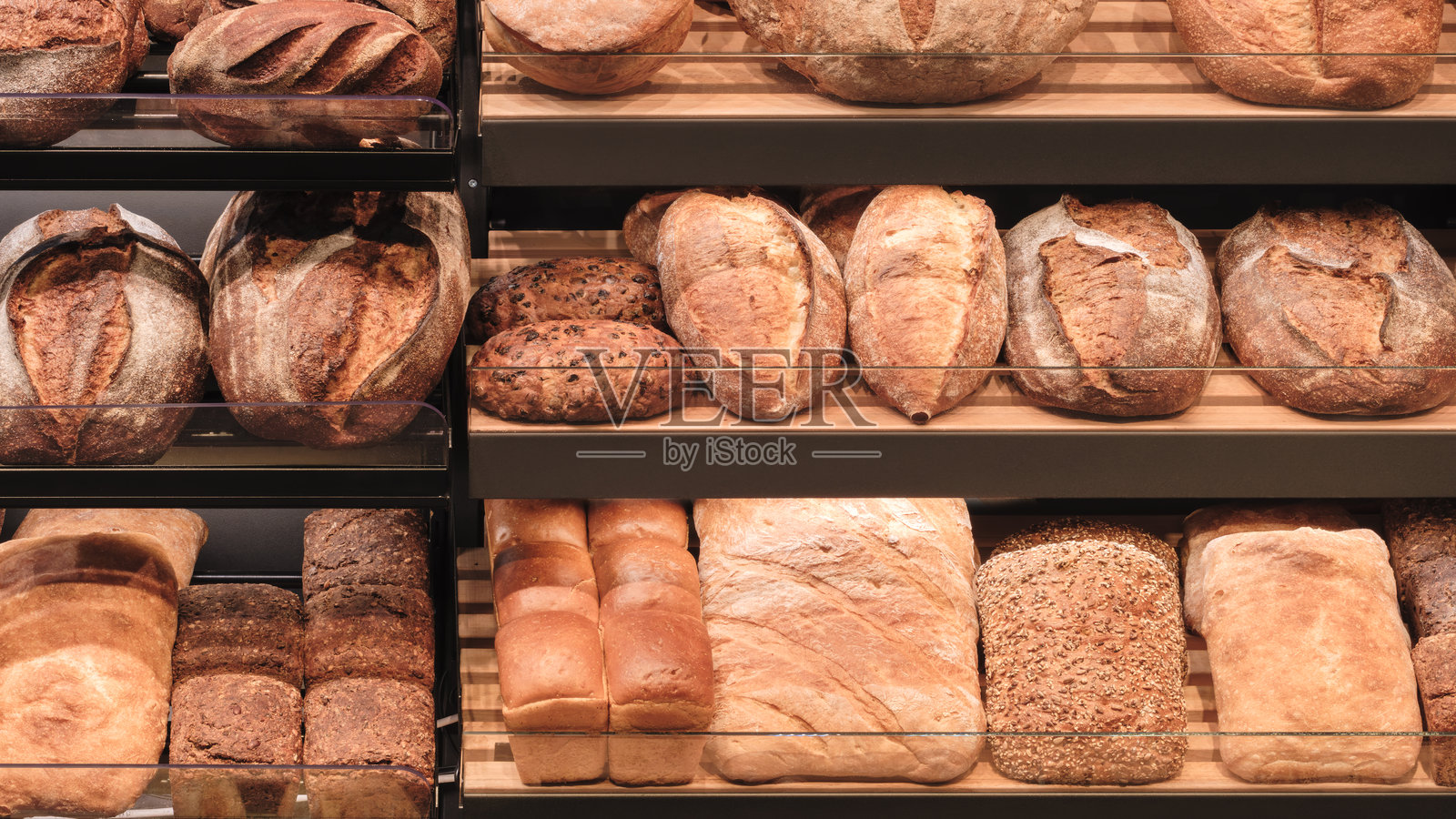 面包店展示架上摆放着各种面包,包括法棍、面包卷和长条面包照片摄影图片