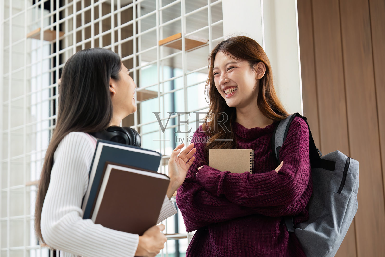 学校生活与友谊。两个愉快的学生在学校走廊里友好地交谈。照片摄影图片