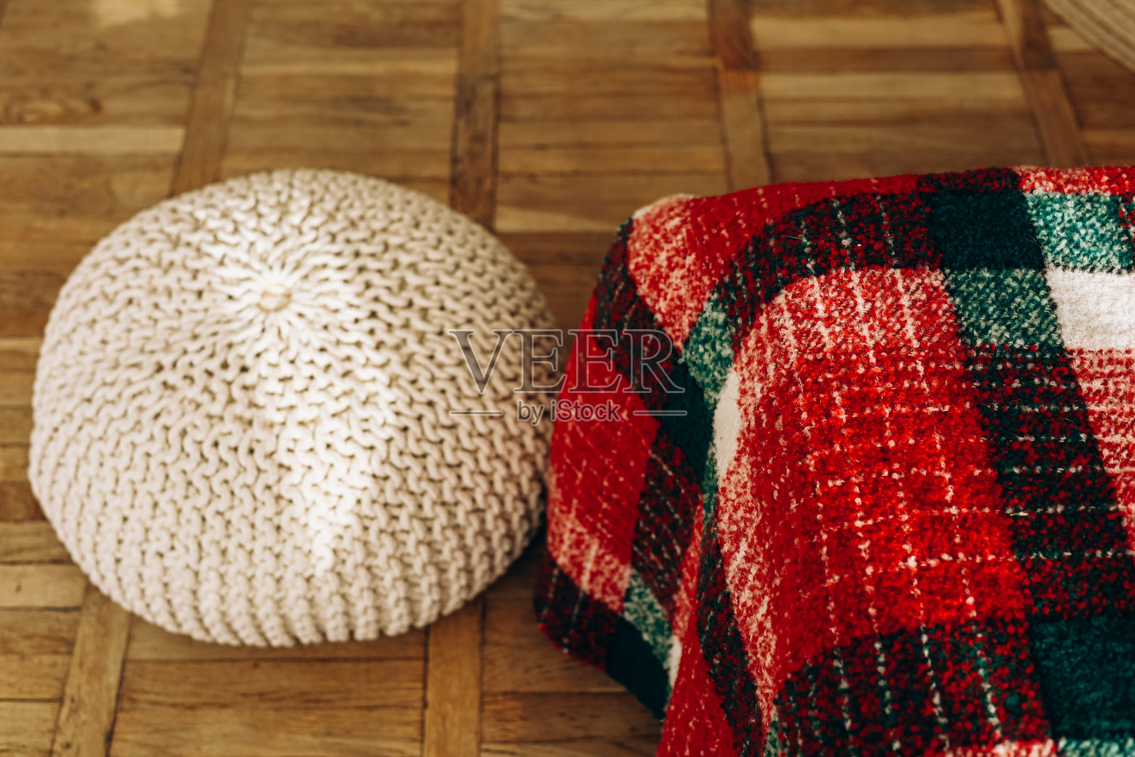 舒适的针织坐垫和格子毛毯放在木地板上,营造温馨的居住空间装饰照片摄影图片