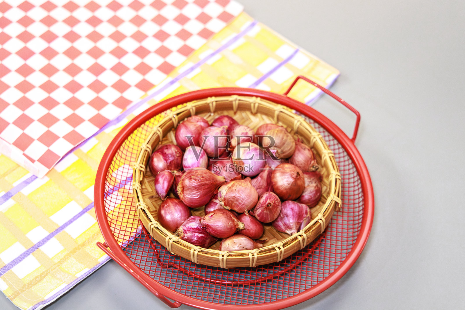 一篮红洋葱放在红黄格子布上照片摄影图片