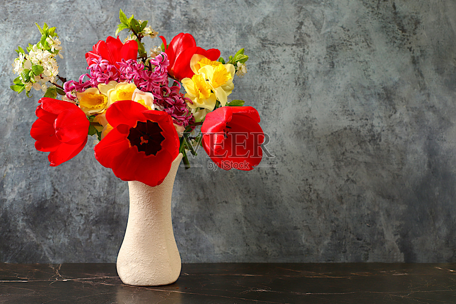 美丽的春季盛开的郁金香、水仙花、风信子和樱花枝在优雅背景下的花瓶中。抽象的花卉排列和屏幕横幅,静物,带有夏季问候概念的花卉节日贺卡。照片摄影图片