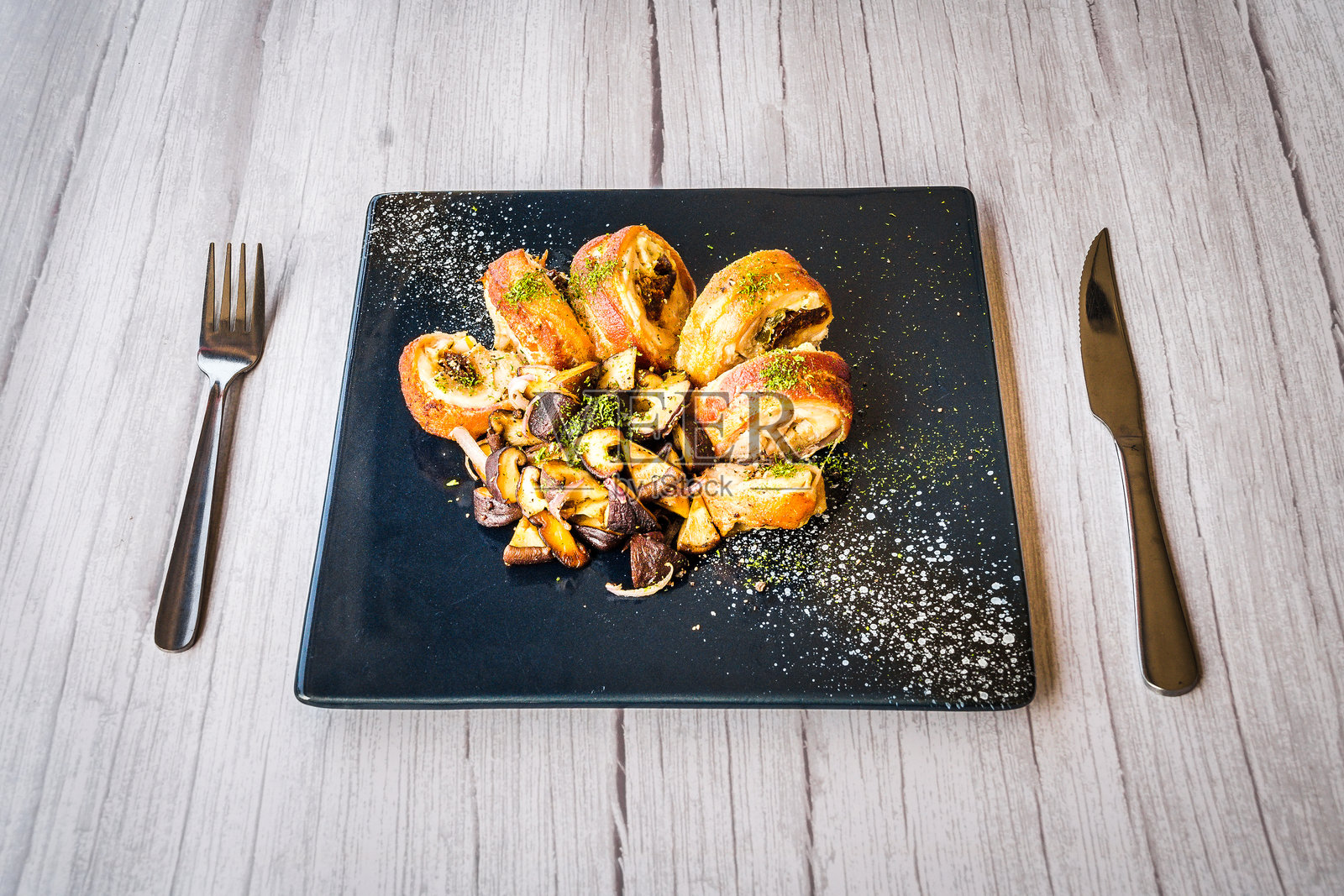 鸡肉卷配炒蘑菇,盛放在黑色盘子上照片摄影图片