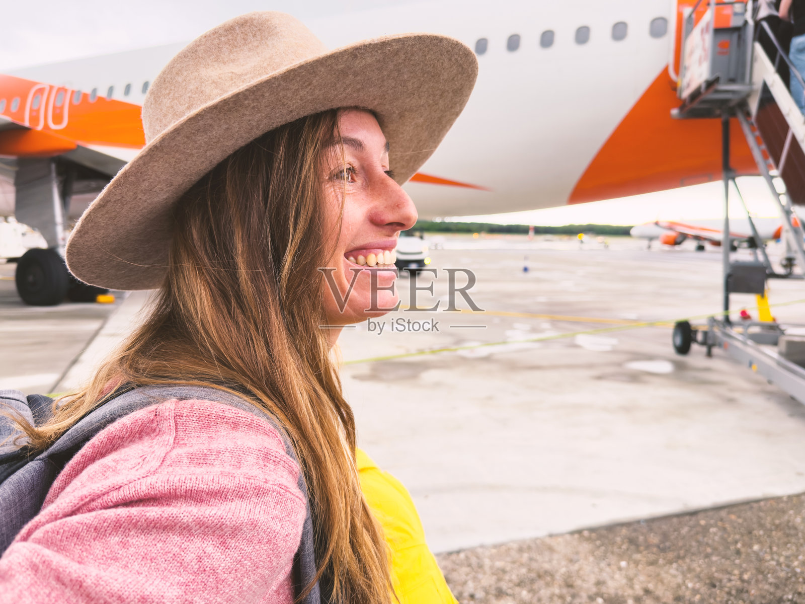 机场背景下微笑的女性与飞机相伴照片摄影图片