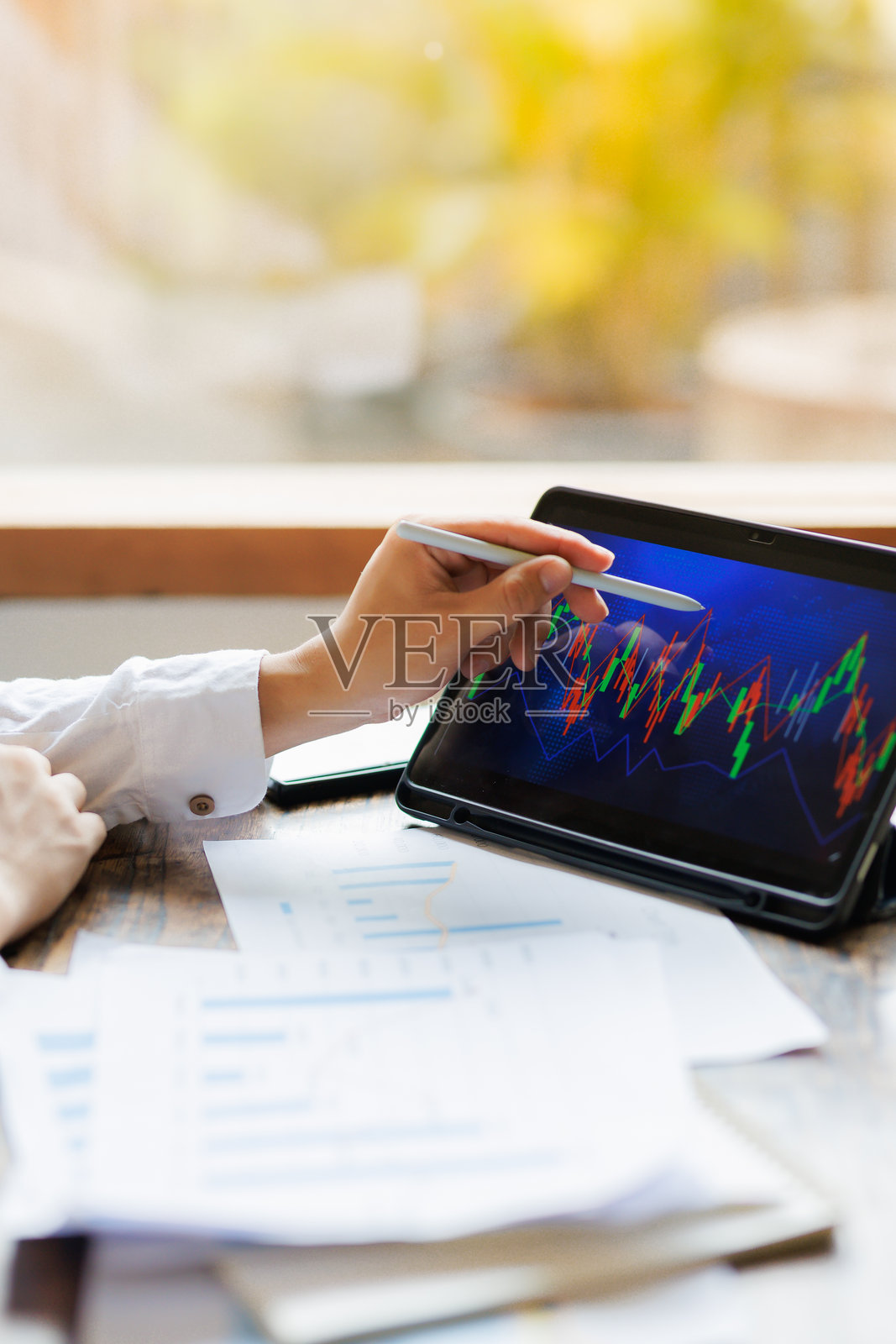 专注于策略的投资者手持市场分析报告,旁边有一台显示实时波动图表的平板电脑。照片摄影图片