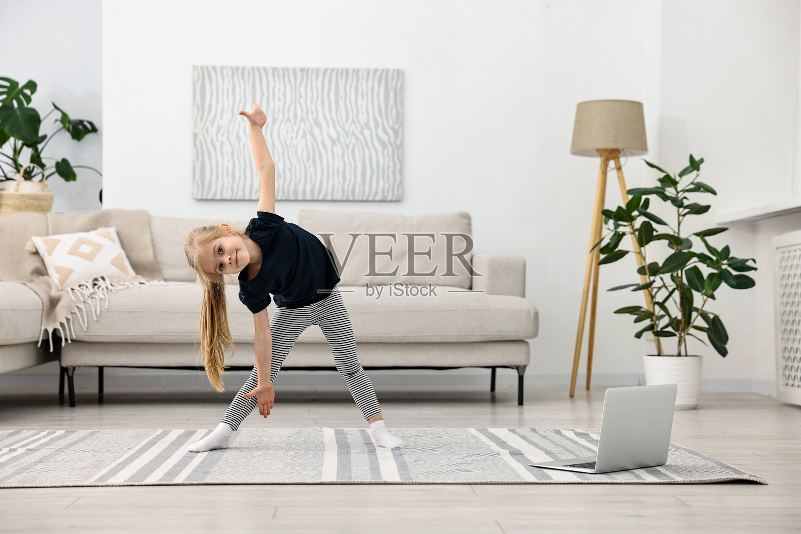 小女孩在家通过笔记本电脑与在线教练锻炼。运动活动照片摄影图片