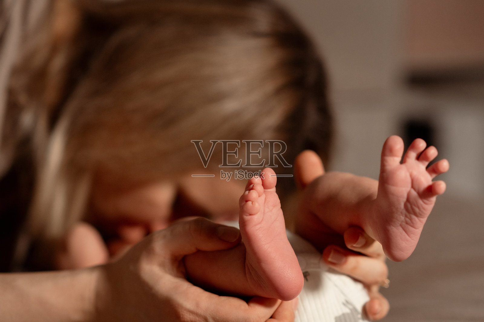 温馨的母婴时刻,柔和的焦点聚焦在温暖室内环境中小脚丫上,傍晚时分。照片摄影图片
