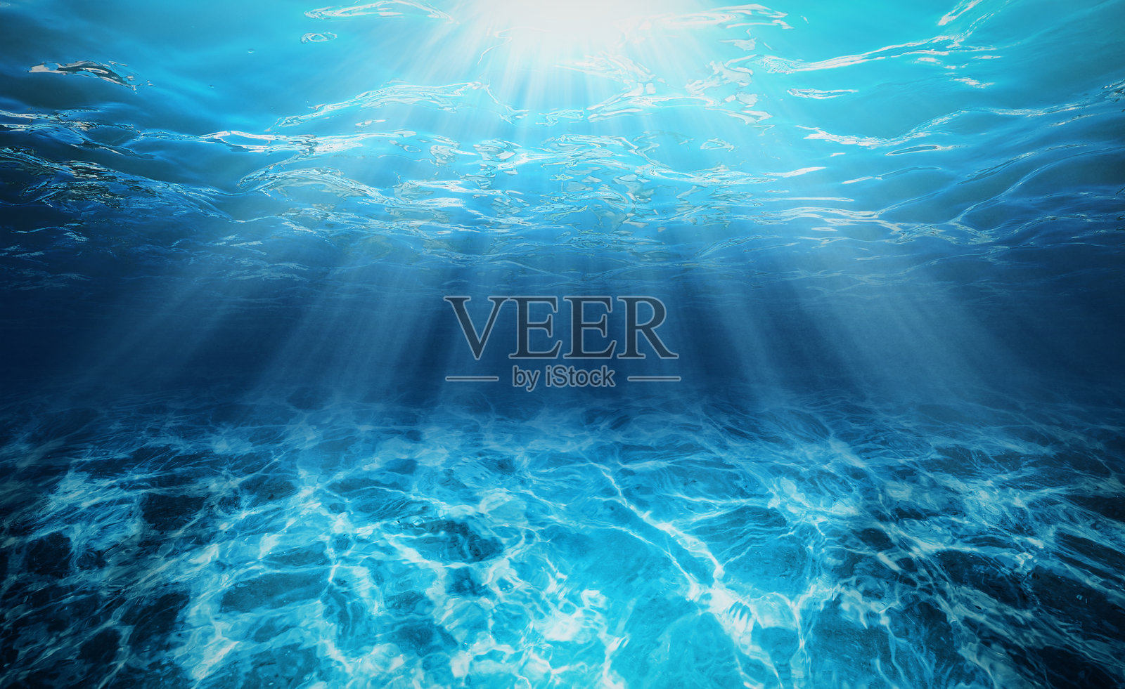 深海深渊中的阳光。清澈的蓝色海洋,照亮了水下的表面。照片摄影图片