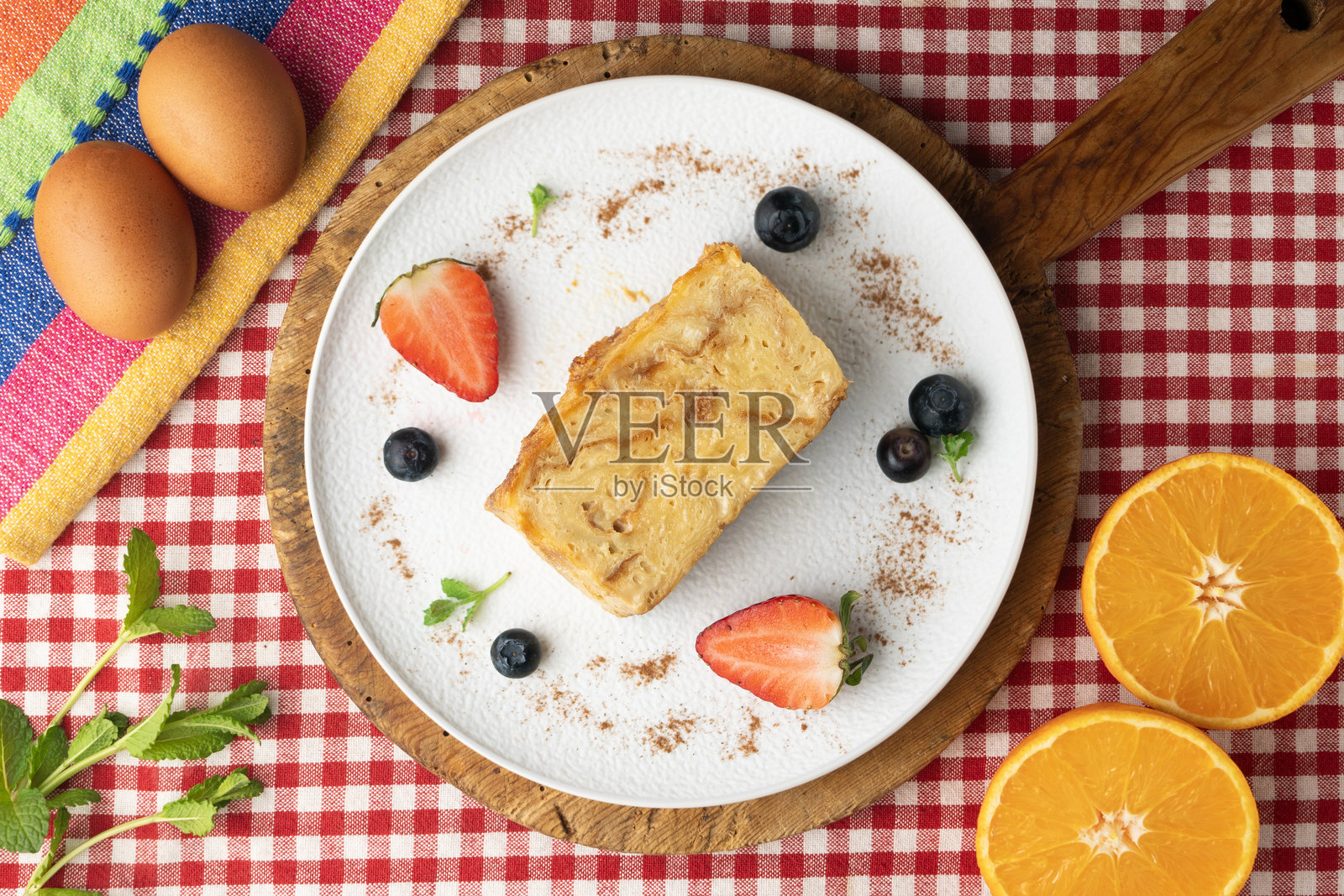 伊比萨岛格雷克索内拉。用来自巴利阿里群岛的传统恩萨伊马达制作的蛋布丁。顶部视角的桌子上摆放着圣诞装饰。照片摄影图片