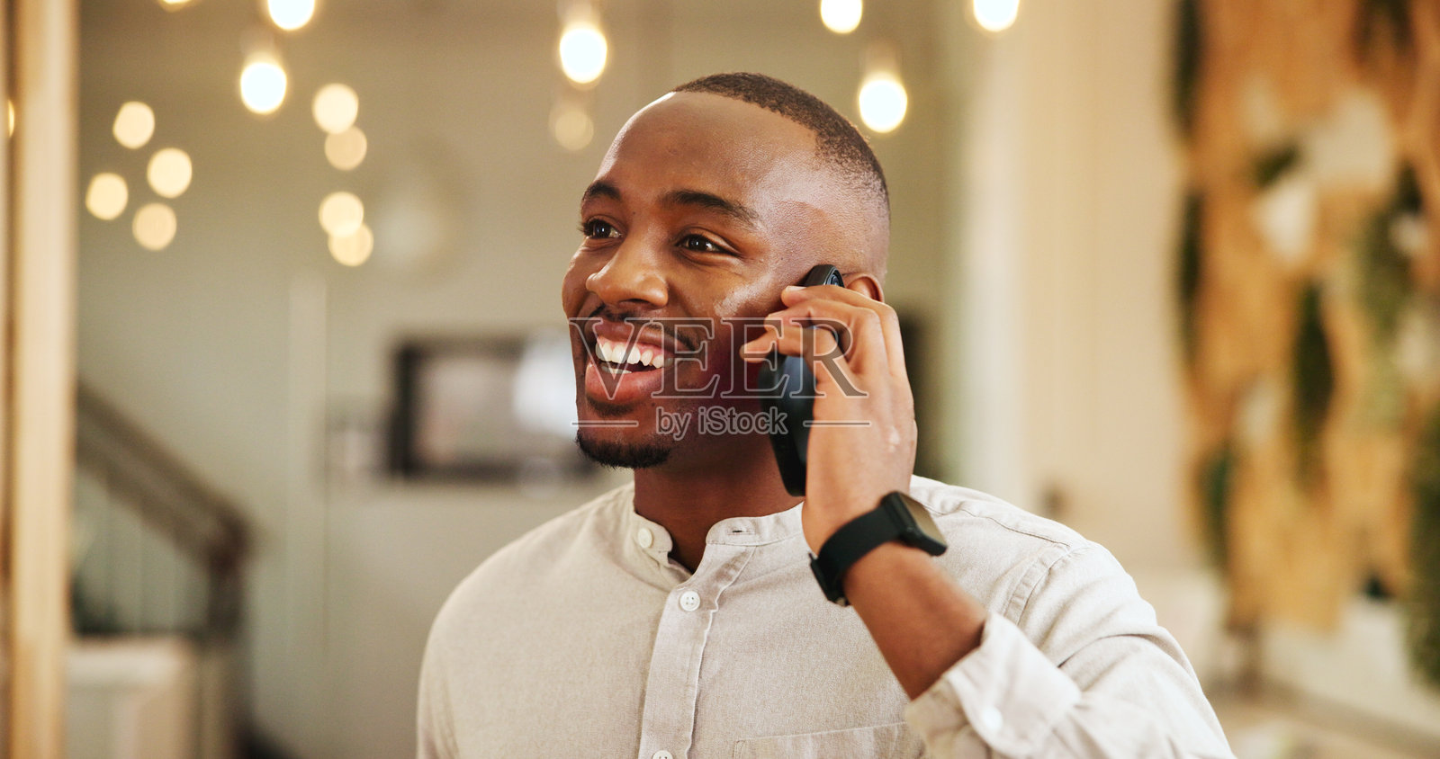 快乐的黑人男性在酒店进行电话沟通,讨论入住、登记或友好交谈。微笑的男性客户或用户在度假村使用手机进行聊天或通话。照片摄影图片