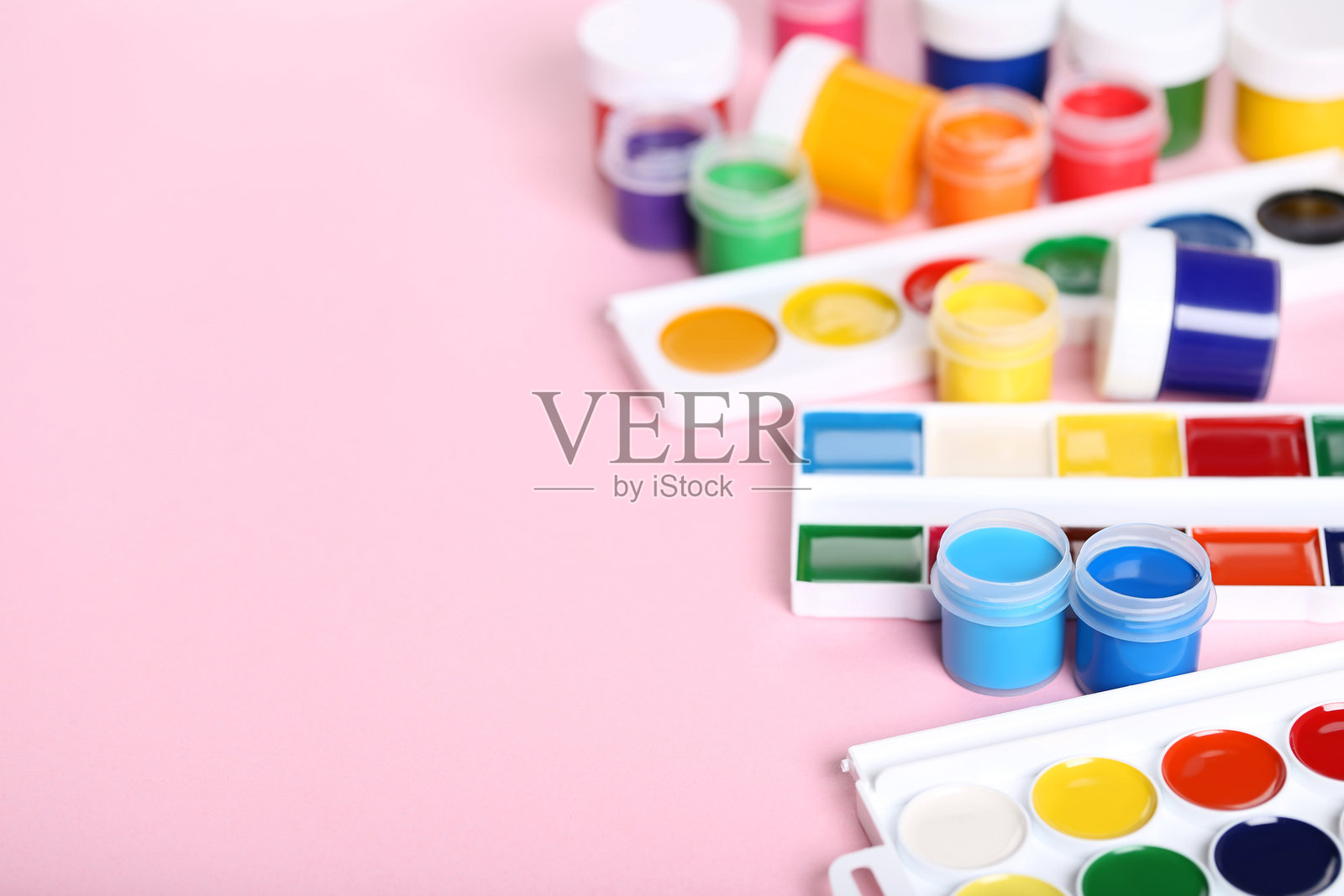 五彩缤纷的水粉颜料在粉色背景上照片摄影图片