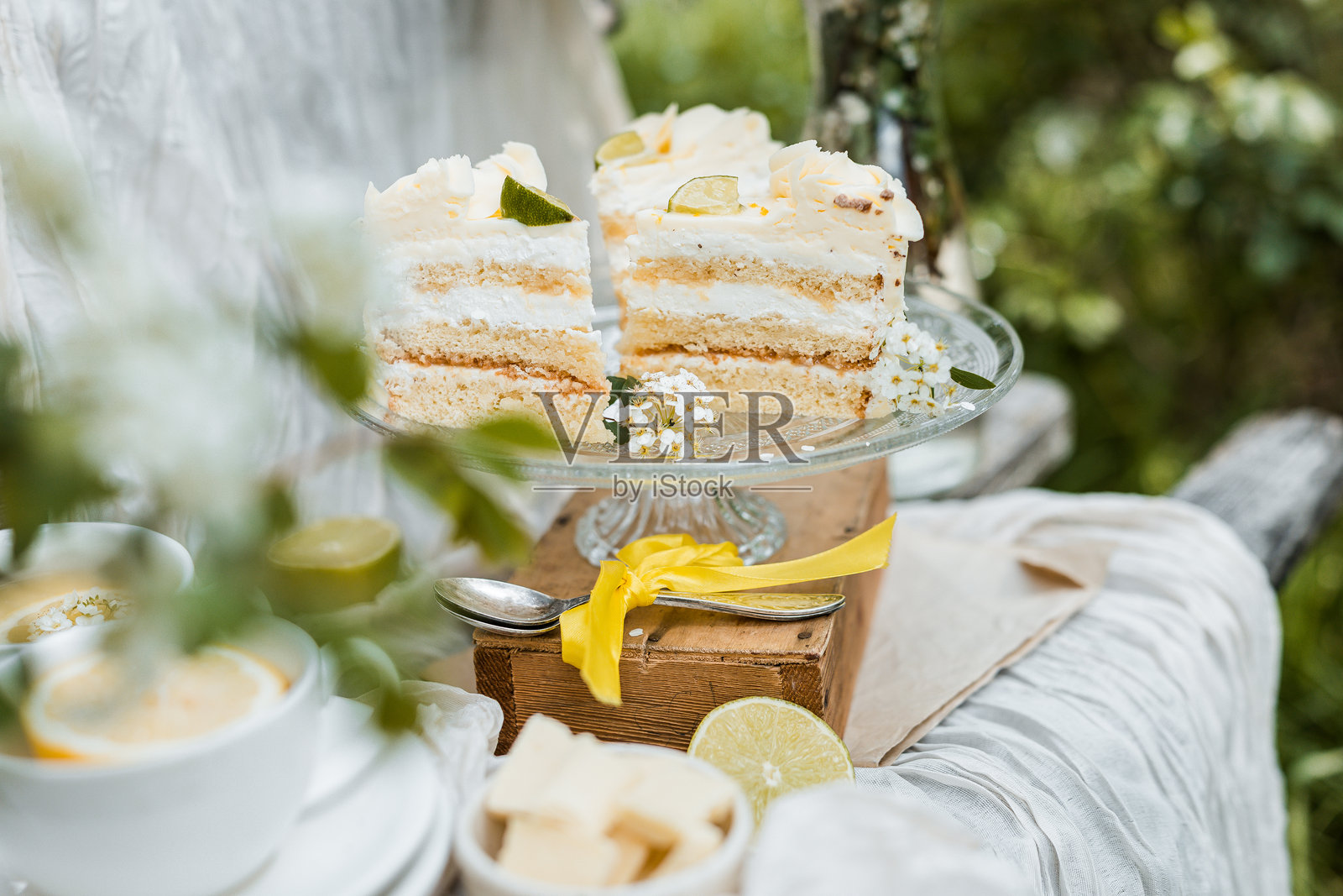 柠檬香气海绵蛋糕切片,淋上白巧克力,精美地摆放在古董陶瓷盘上,配有蕾丝餐垫、干薰衣草和乡村风格的木桌布置。照片摄影图片