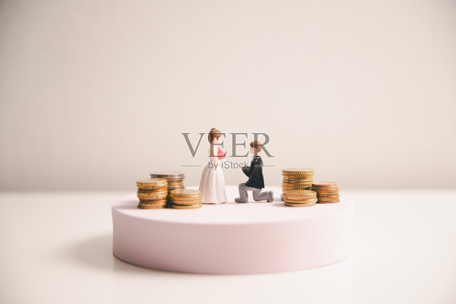 为婚礼储蓄和婚礼策划的概念。可持续的家庭生活或婚姻生活的财务目标。微型婚礼在一排排上升的硬币上,描绘了新家庭的储蓄或增长。照片摄影图片