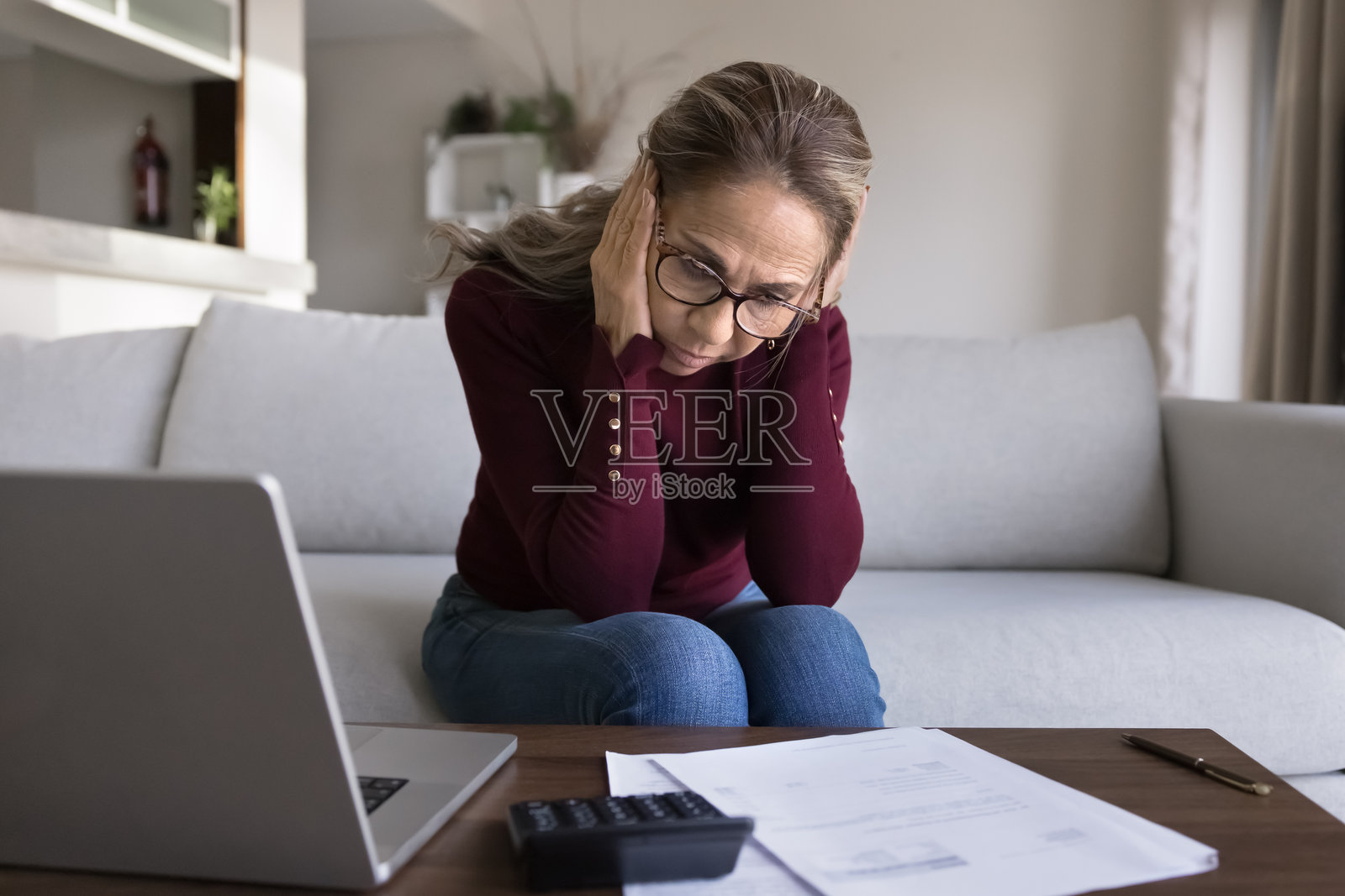 震惊且沮丧的退休拉丁裔女士在计算超支的金额照片摄影图片