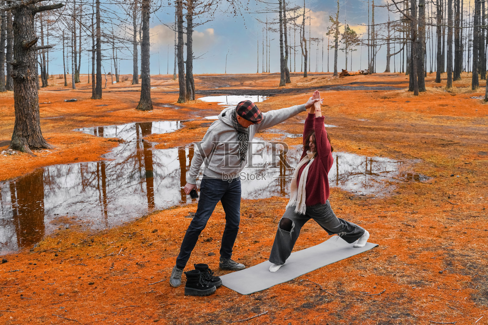 健身教练在宁静的森林环境中指导年轻女性的锻炼,周围是生机勃勃的秋季色彩。照片摄影图片