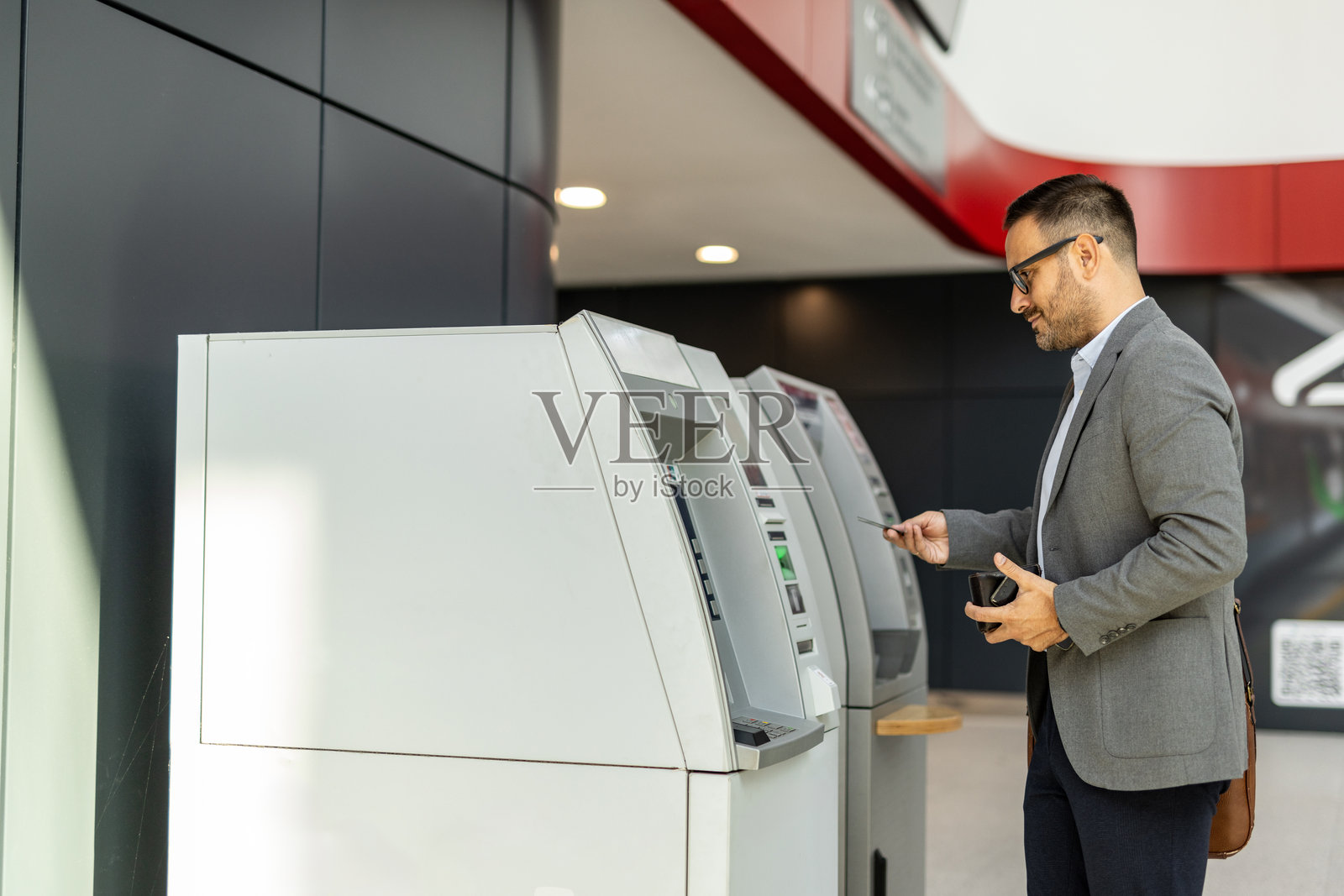 商人使用自动取款机进行银行交易照片摄影图片