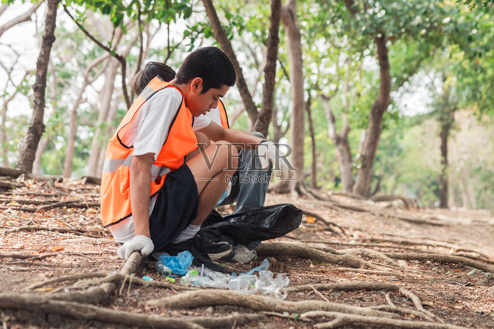 一群朋友和年轻志愿者在户外慈善活动中收集垃圾,提高意识并促进环保社区行动。照片摄影图片