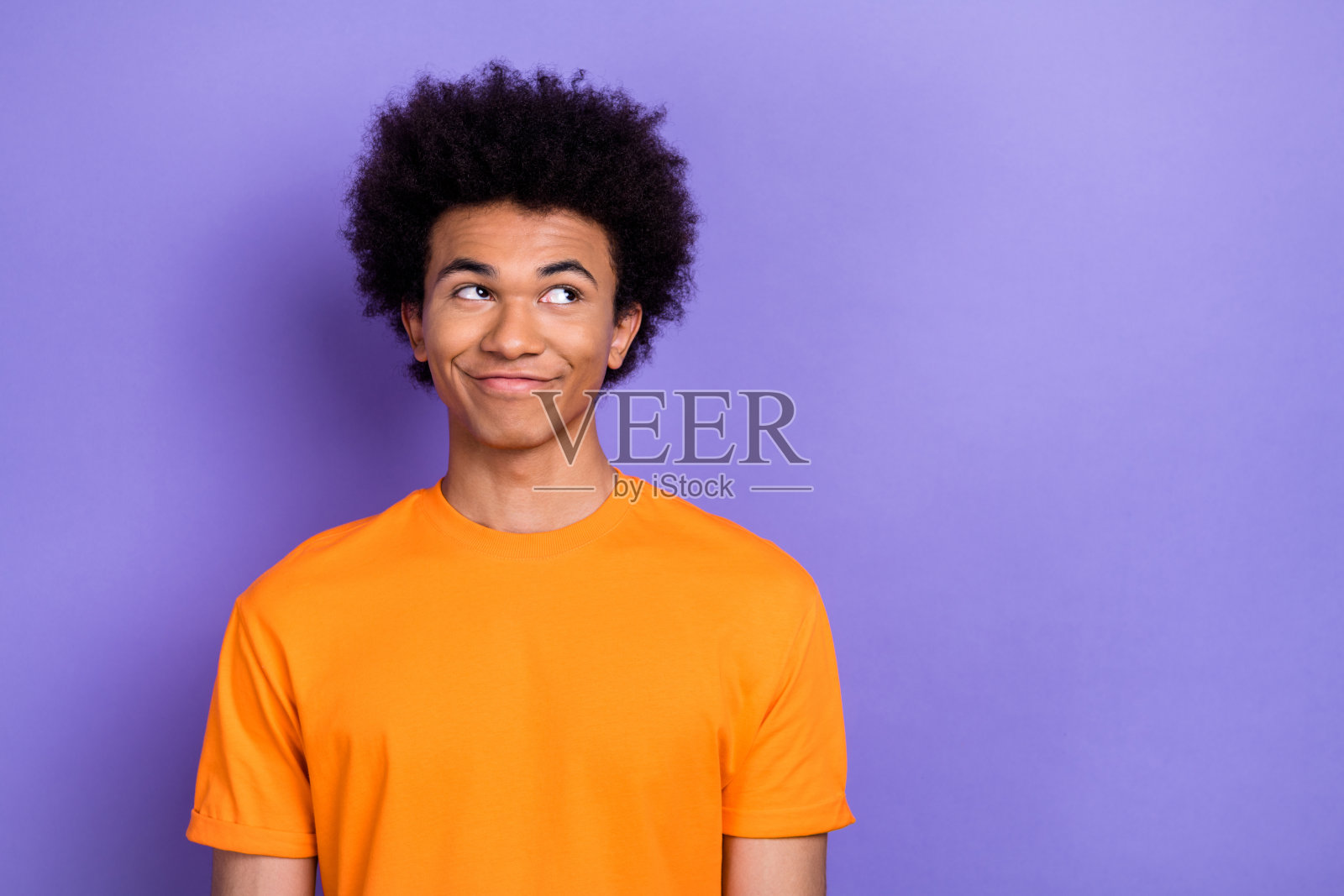 积极思考的人物肖像,面带兴趣地凝视空旷的空间,独自站在紫色背景前。照片摄影图片