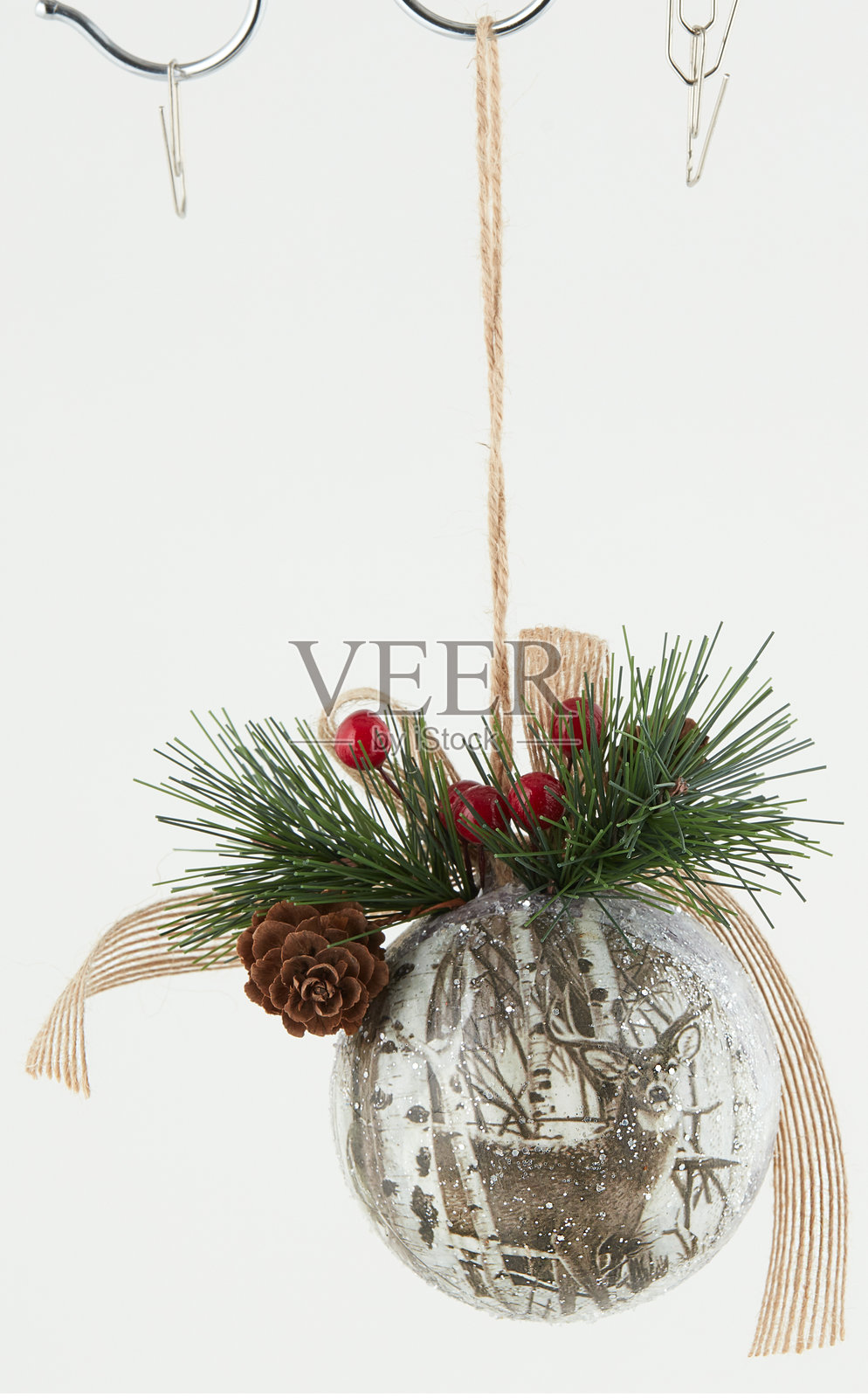 挂在绳子上的圣诞球,周围有绿色松针,背景为自然风景,带有抠图路径。照片摄影图片