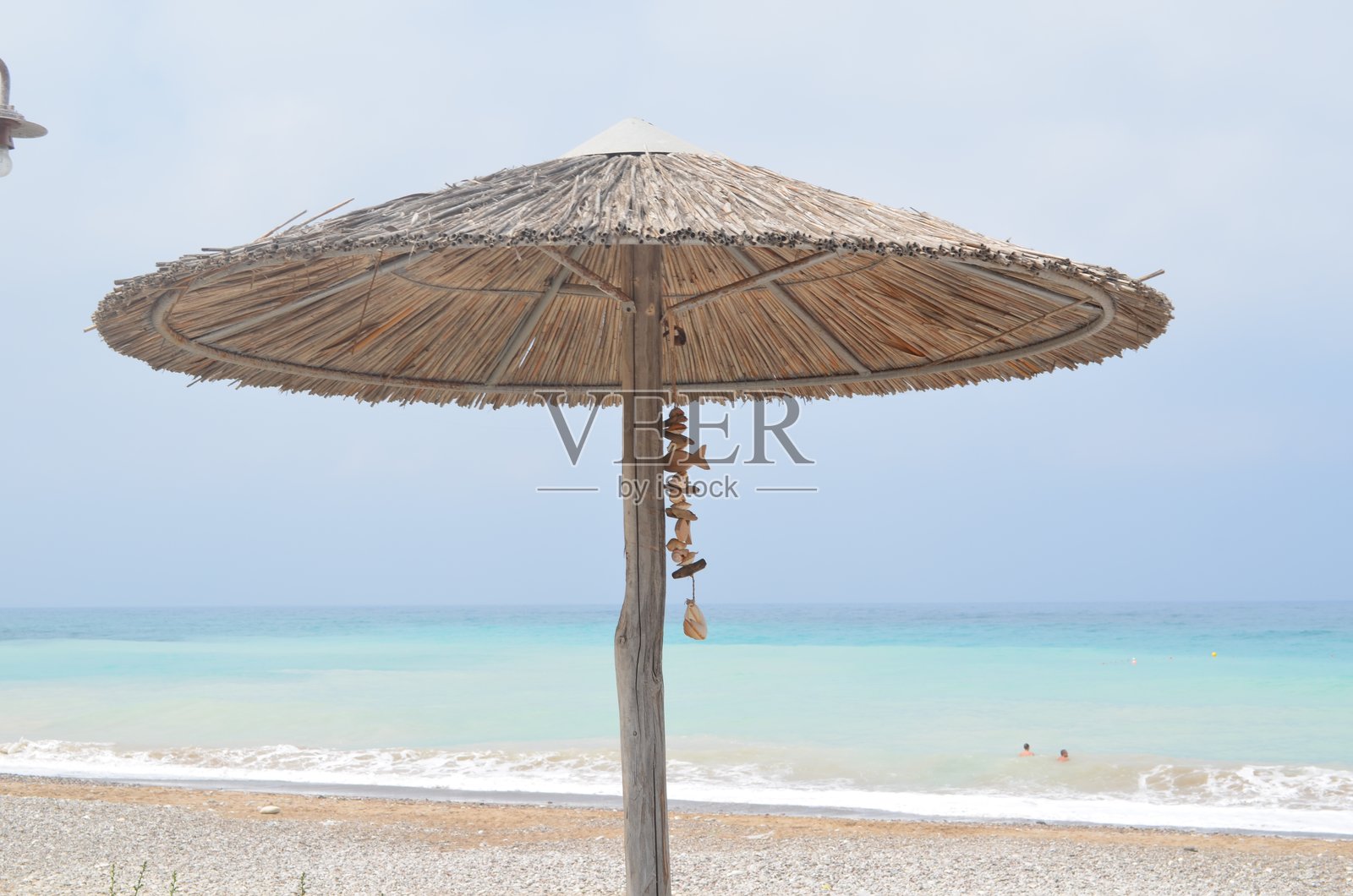 阳光明媚的海滩上有草编伞,俯瞰着碧蓝的海洋照片摄影图片
