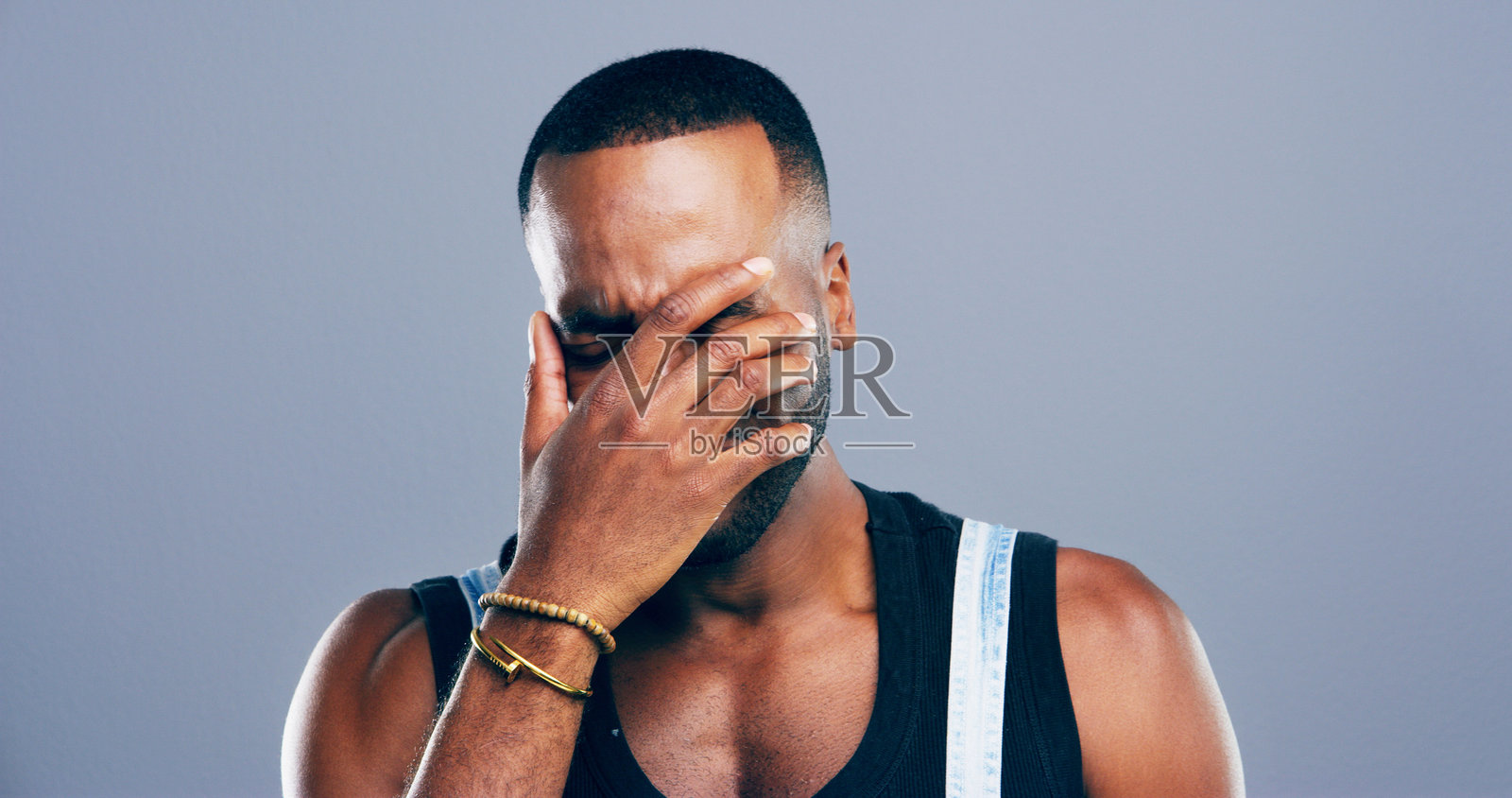 非洲男子在工作室中因悲伤而流泪,经历抑郁、哀悼失去和情感记忆。此人感到悲伤,处于心理健康危机、坏消息和创伤后应激障碍的模拟空间,背景为灰色。照片摄影图片