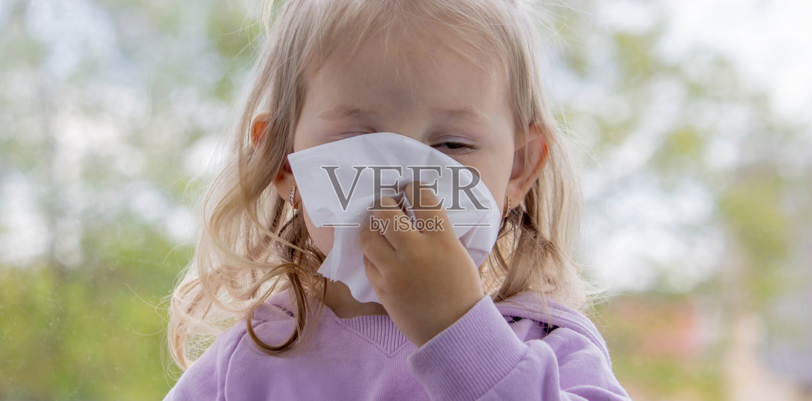 小孩用纸巾擦鼻涕,感冒了。选择性聚焦。照片摄影图片