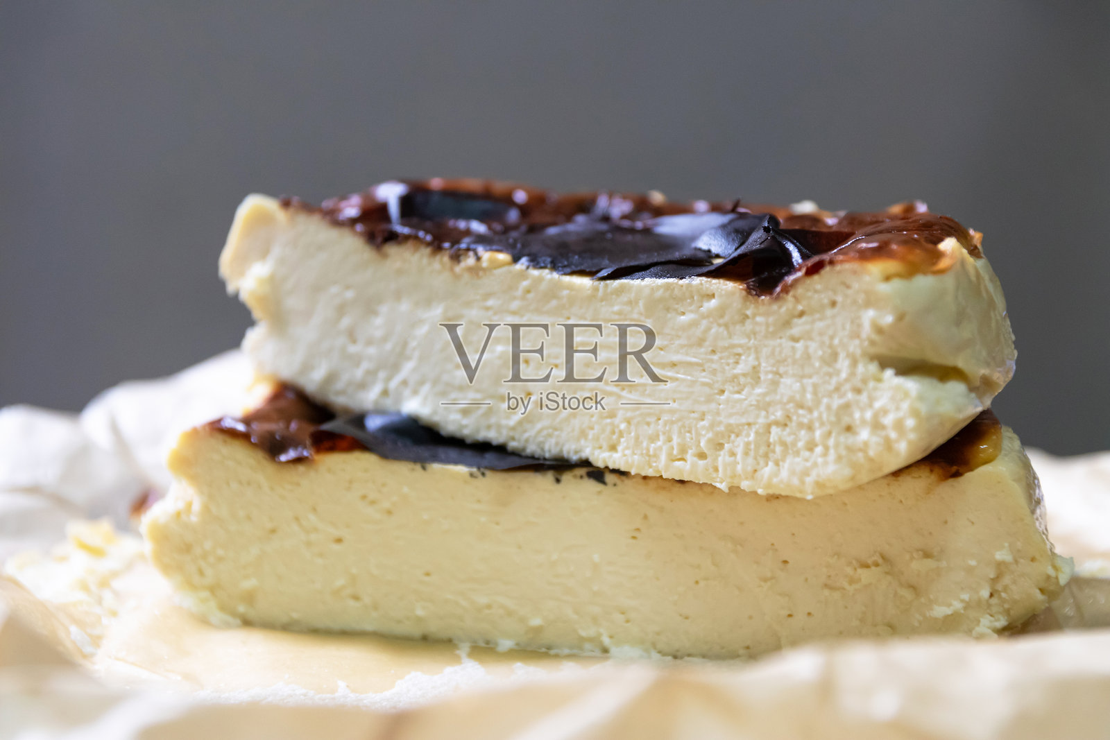 巴斯克焦 burnt cheesecake 放在盘子上,旁边有一块蛋糕照片摄影图片