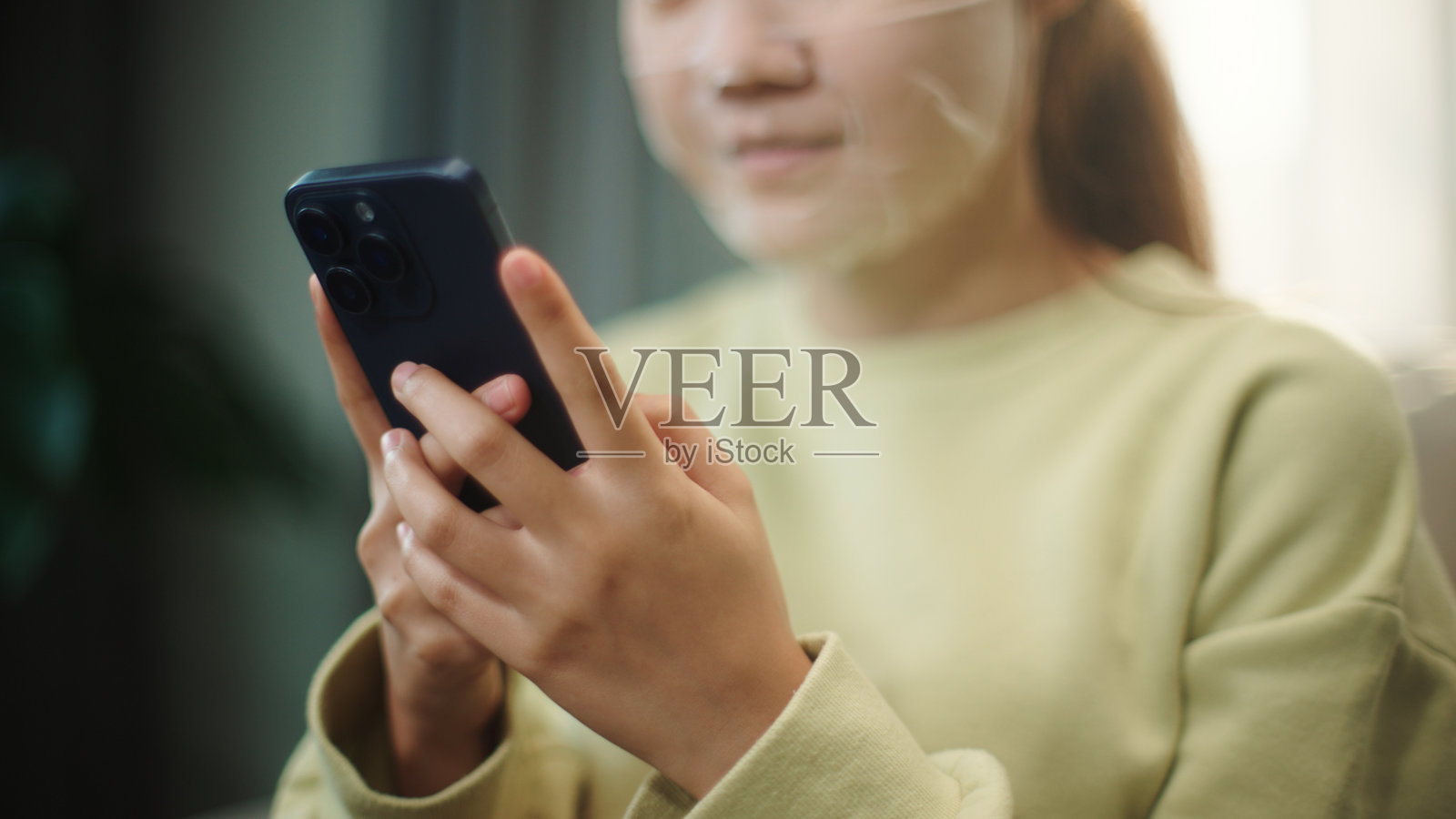 戴着面膜的青少年使用智能手机。照片摄影图片