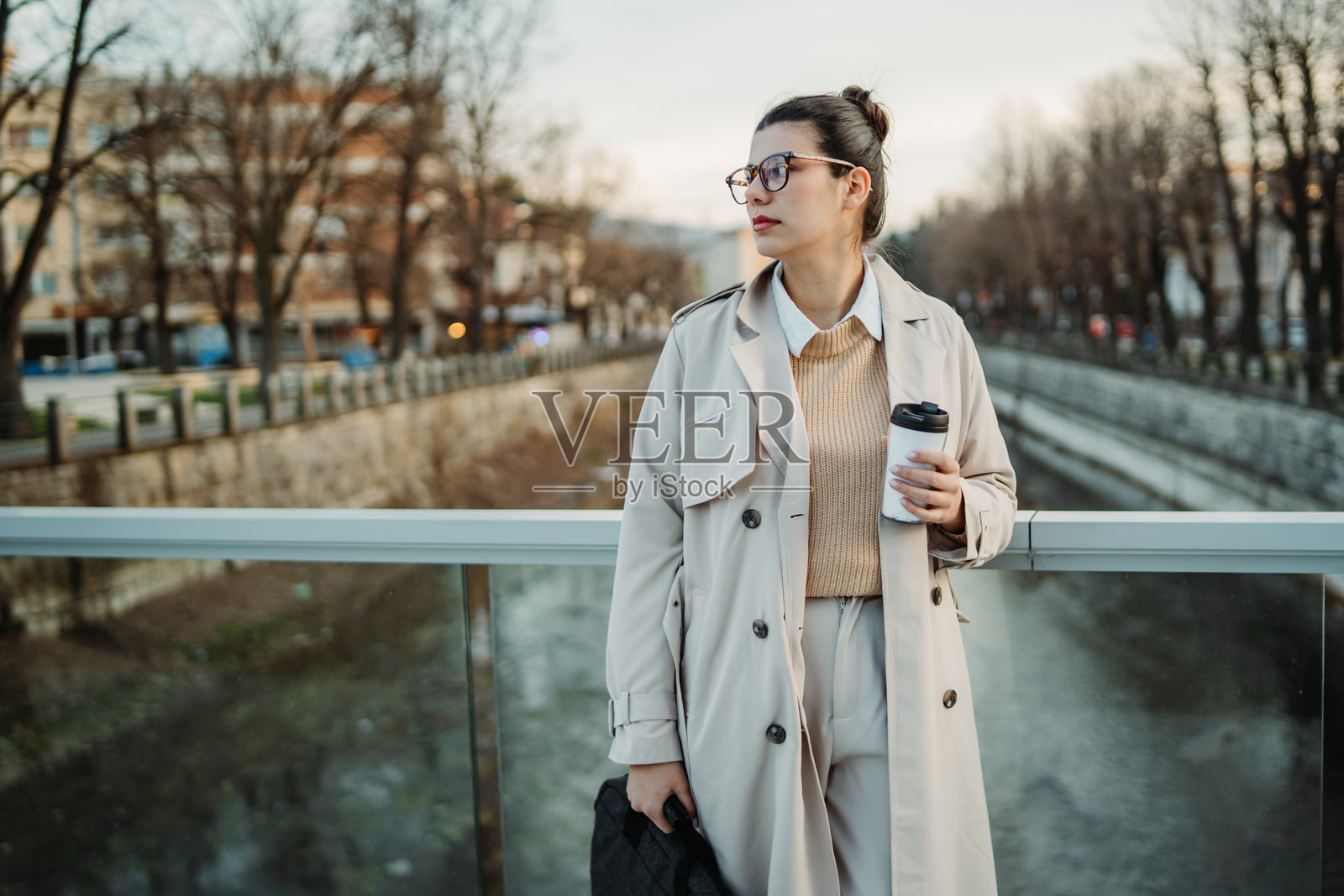 年轻的白人女性下班回家,喝着咖啡并使用手机。照片摄影图片