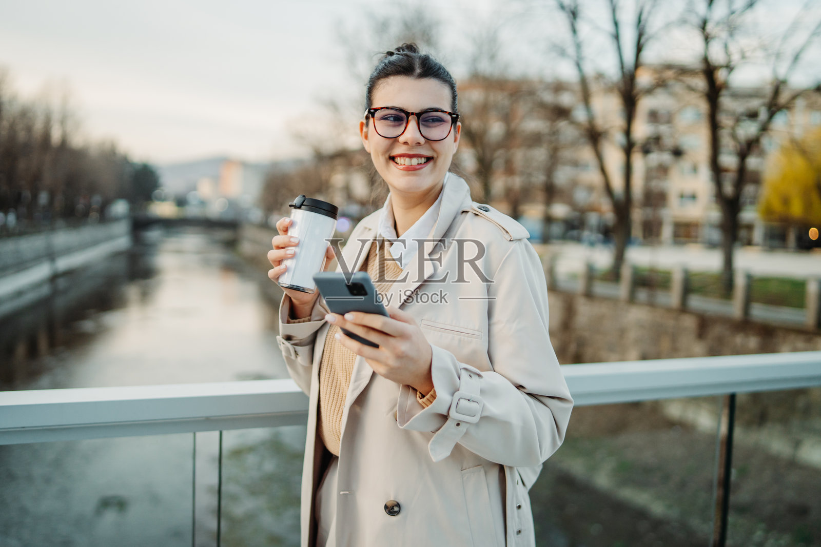 年轻的白人女性下班回家,喝着咖啡并使用手机。照片摄影图片