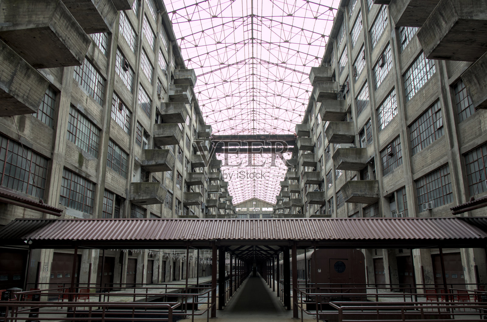 布鲁克林军械库大楼内废弃的中庭景观,带有阳台和铁轨(阴郁的仓库工业综合体,配有玻璃窗)反乌托邦科幻小说破败的景象照片摄影图片