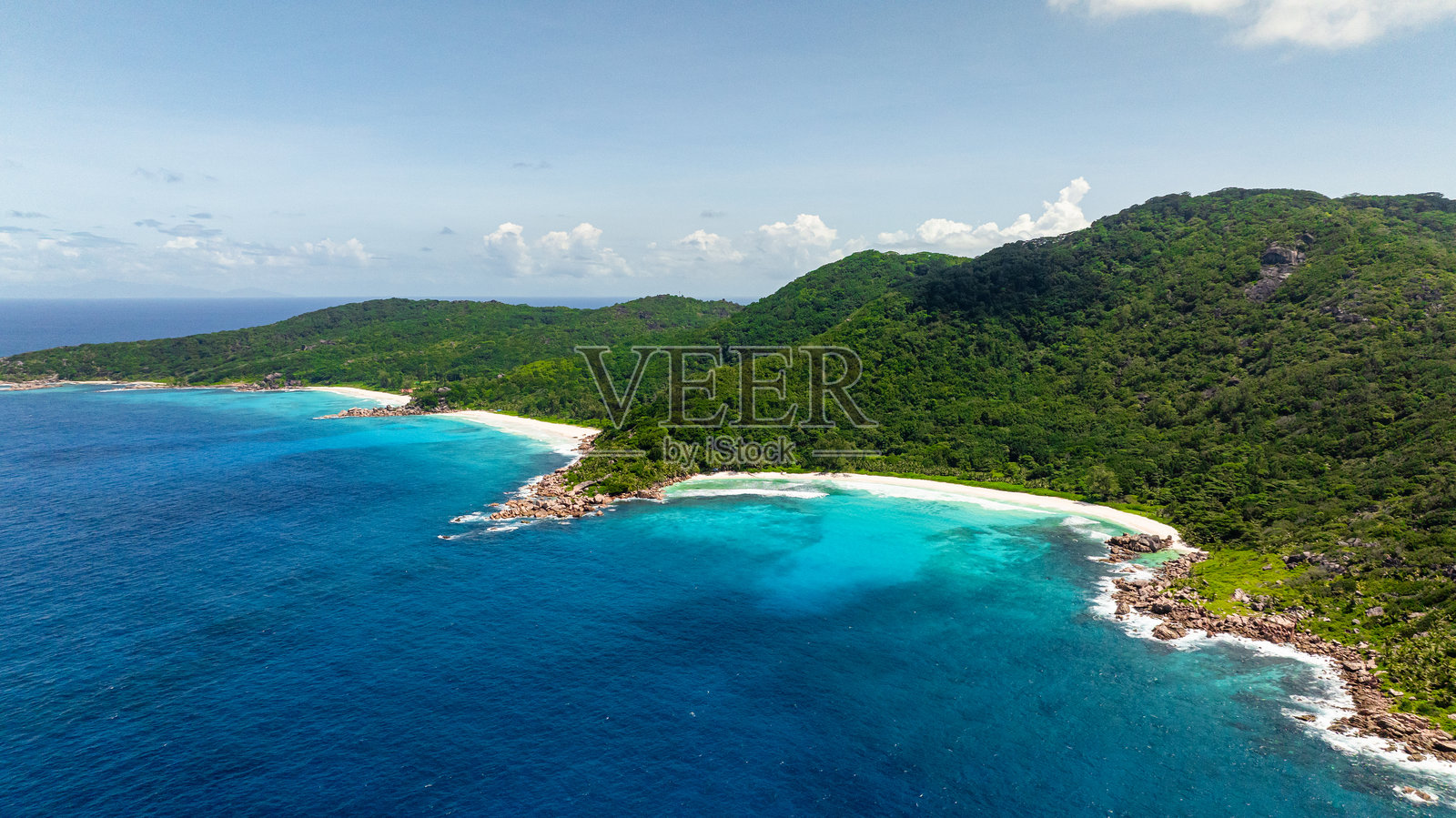 热带海滩小湾,白色沙滩和郁郁葱葱的山丘。照片摄影图片