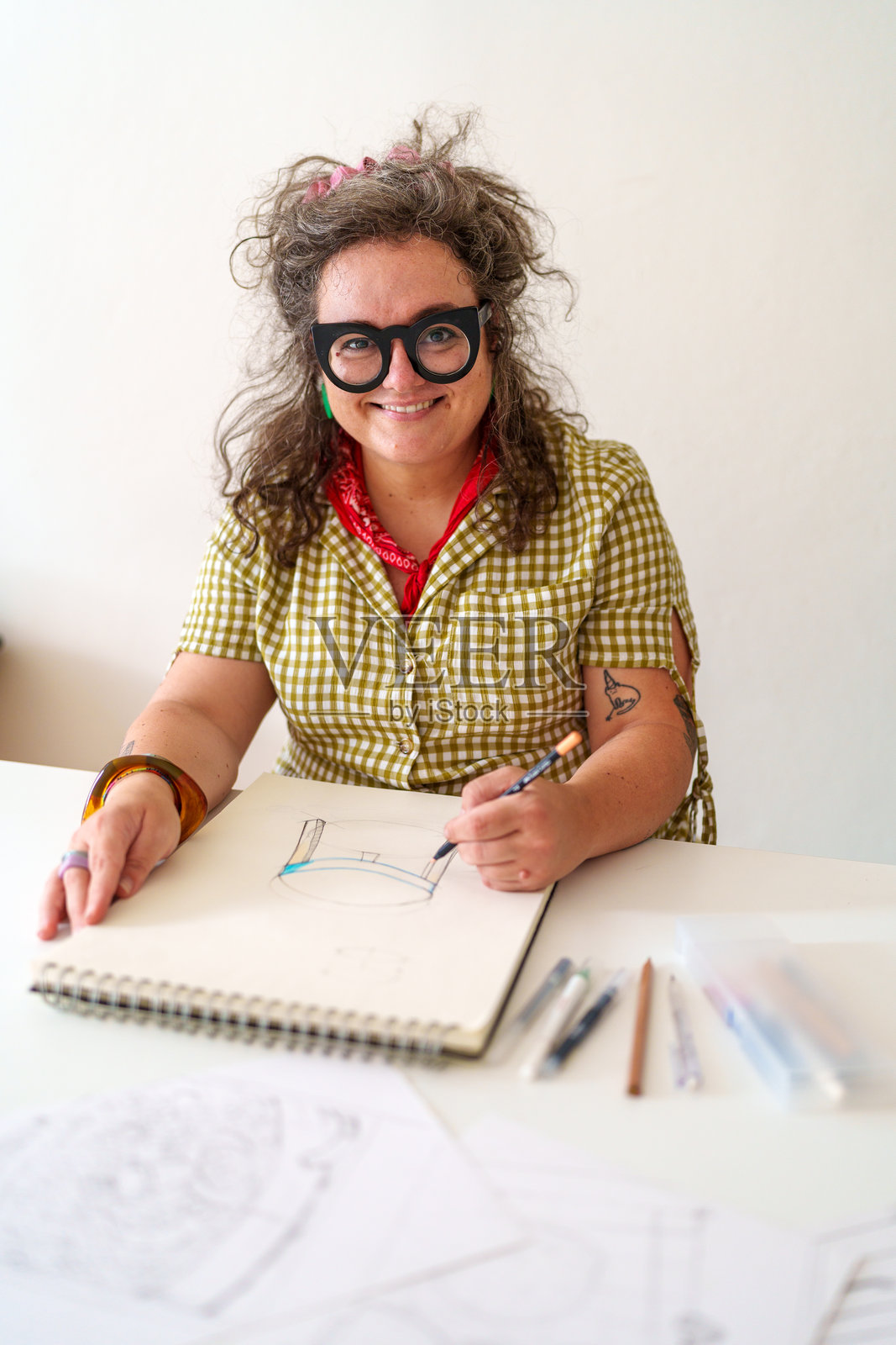 家具设计师在工作室里绘制桌子,面带微笑地看向镜头。照片摄影图片