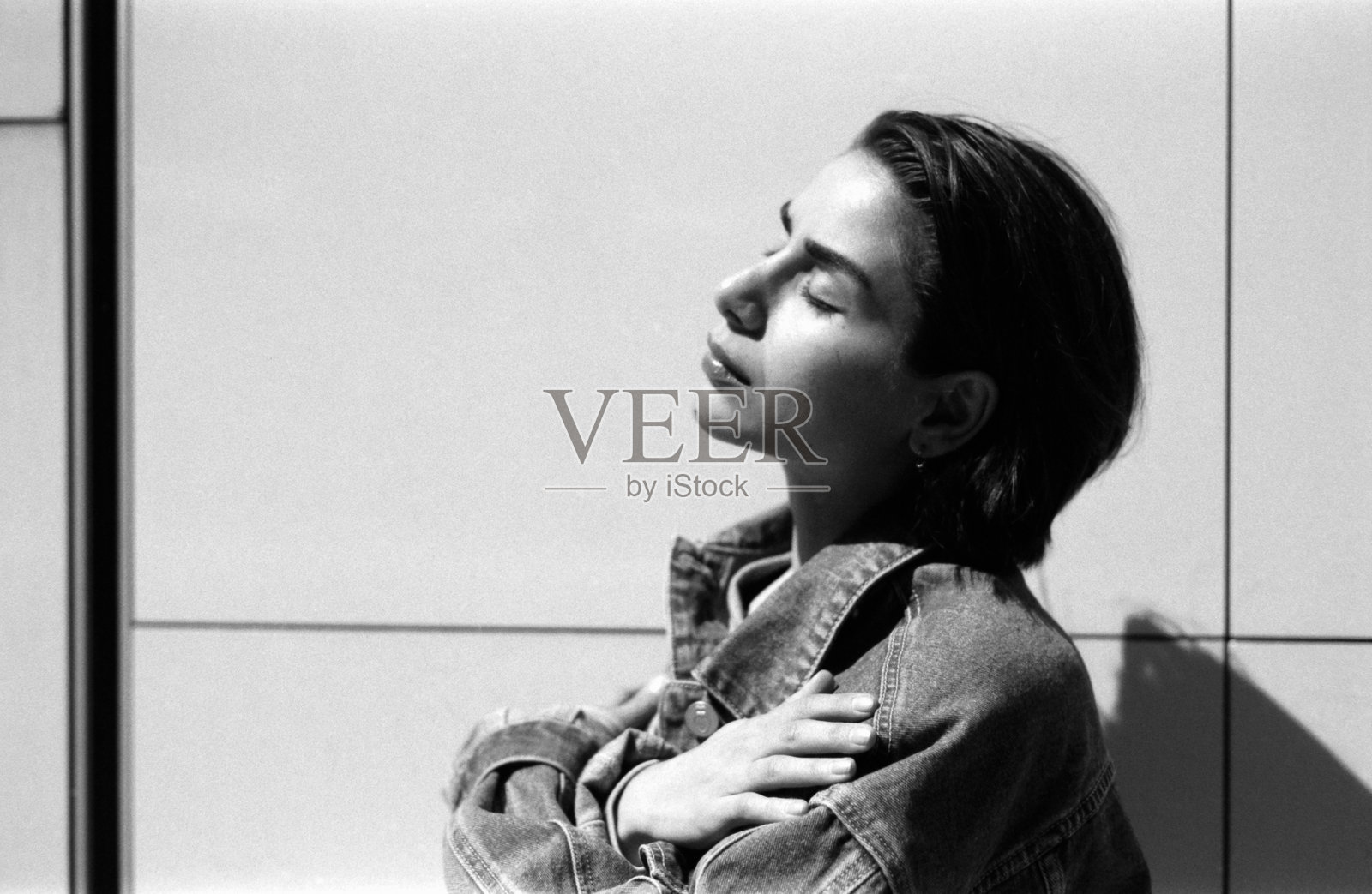 年轻女性穿着牛仔夹克,自我拥抱,颗粒感的胶卷照片照片摄影图片