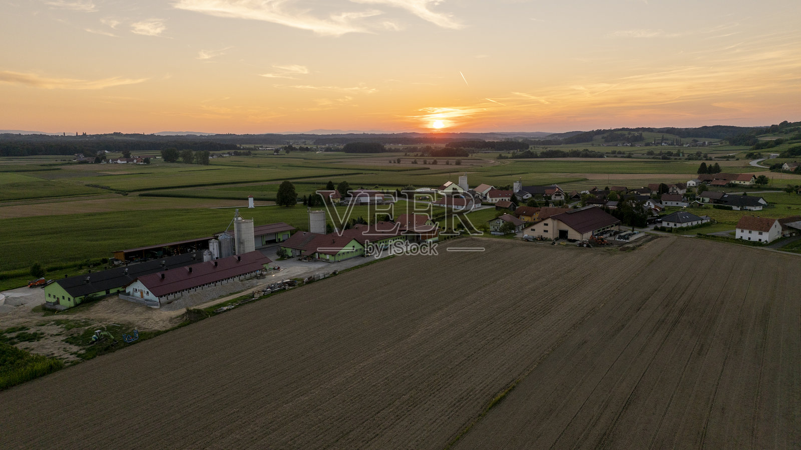 宁静的乡村村庄和日落时分的田野,绚丽的天空和起伏的山丘照片摄影图片