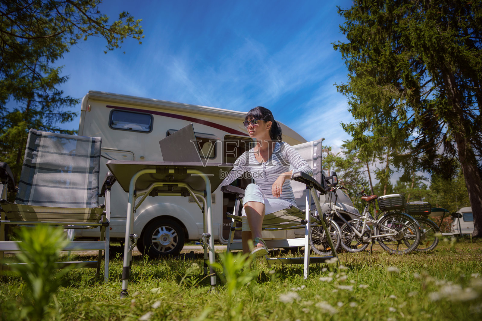女人在露营附近看平板电脑。家庭度假旅行,房车假期。照片摄影图片