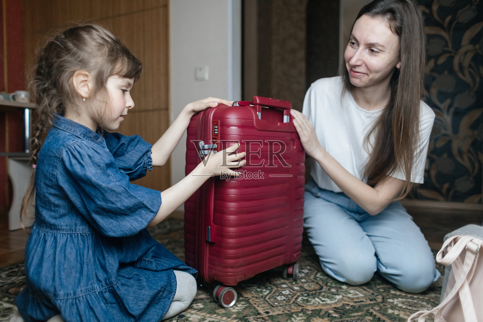 疲惫的母亲与6岁女儿一起打包旅行行李。旅行概念。旅行包的特写以及旅客疲惫的面孔。照片摄影图片