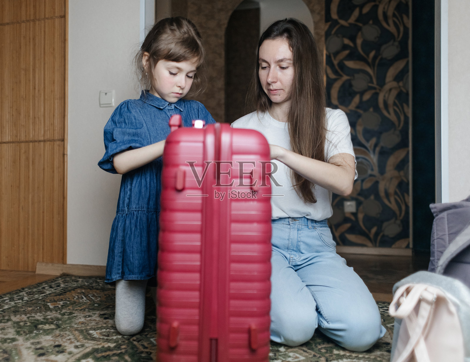 疲惫的母亲与6岁女儿一起打包旅行行李。旅行概念。旅行包的特写以及旅客疲惫的面孔。照片摄影图片