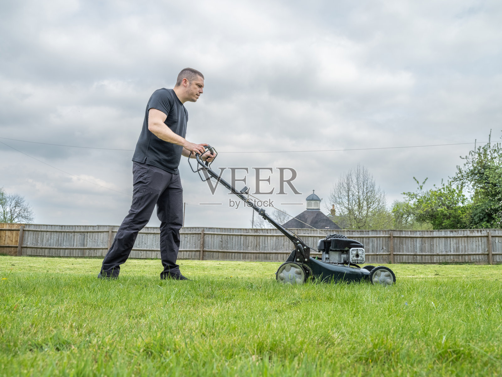 阴天里修剪草坪的男人照片摄影图片