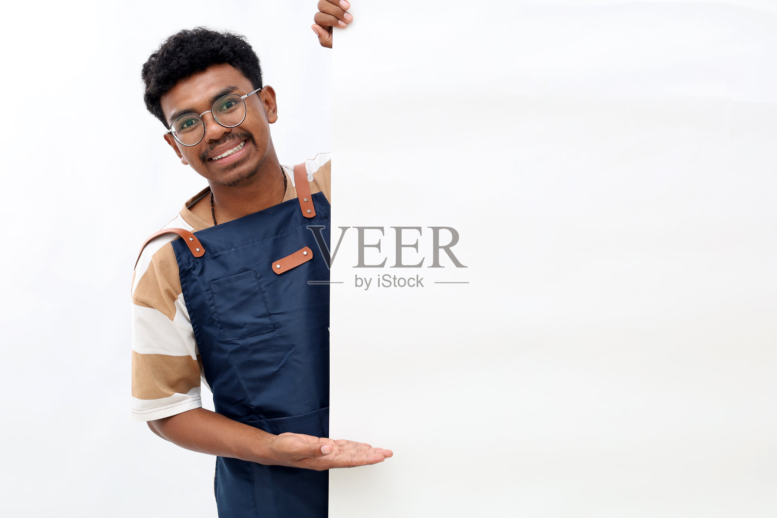 穿围裙的快乐亚洲男子在白色背景的广告板上展示某物照片摄影图片