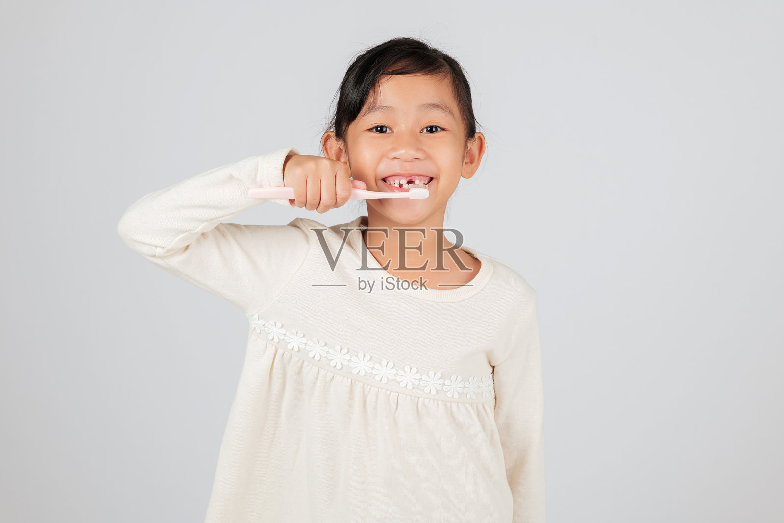 一个缺牙的小孩开心地拿着牙刷。牙医在讨论牙齿缺失的问题。照片摄影图片