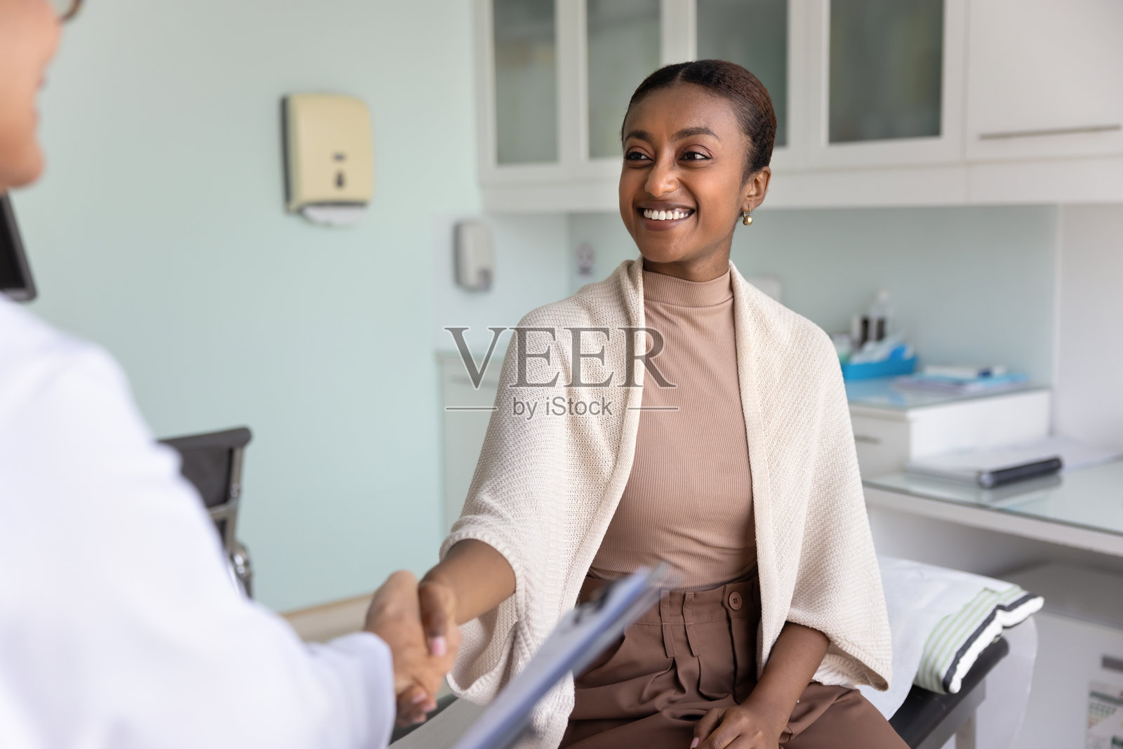 积极健康的年轻非洲患者与女医生握手照片摄影图片